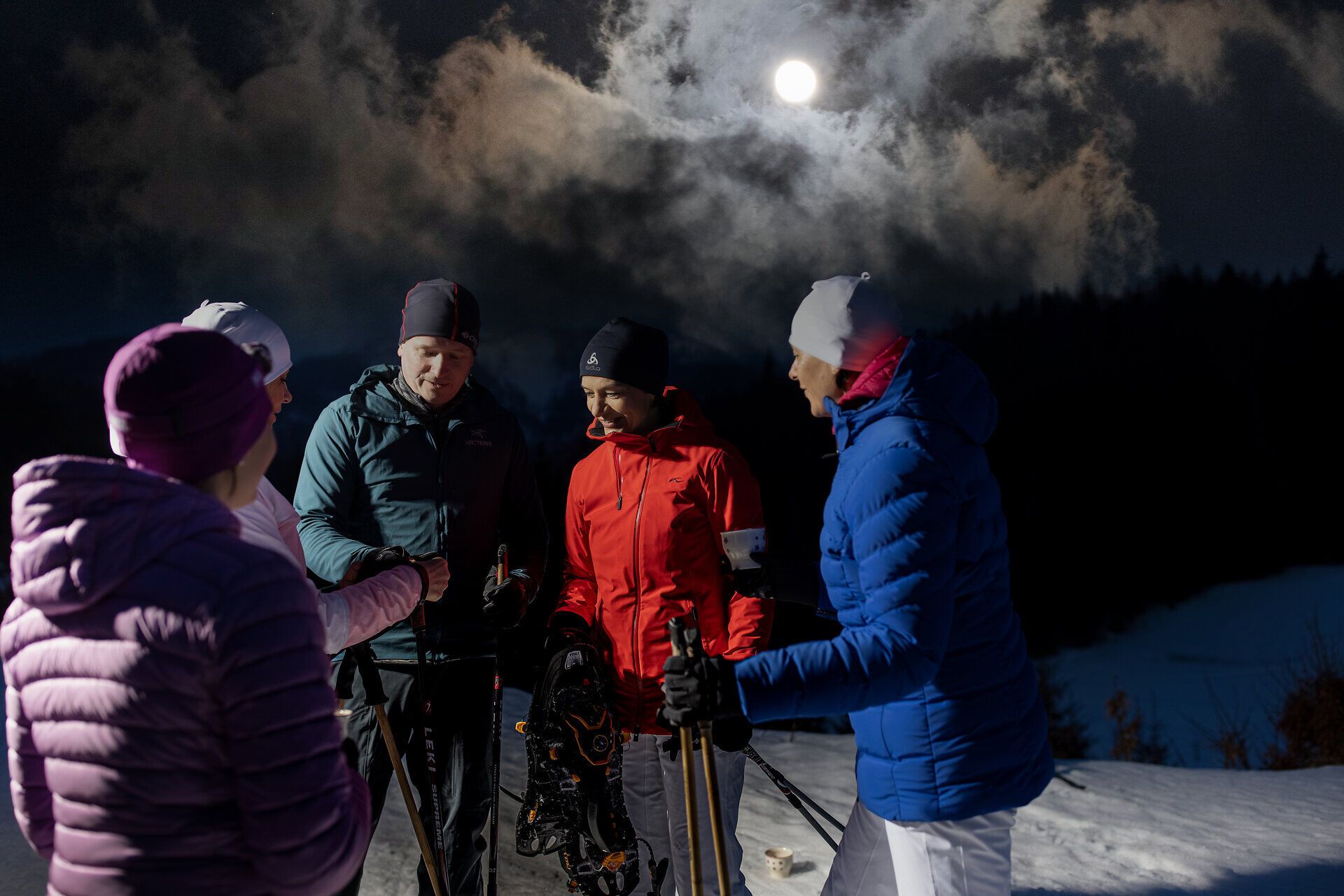 Unter dem sanften Licht des Mondes versammeln sich begeisterte Wanderer, um die winterliche Stille der verschneiten Landschaft zu genießen. Die frische, kalte Luft und das Knirschen des Schnees unter den Schneeschuhen schaffen eine magische Atmosphäre für unvergessliche Erlebnisse in der Natur.