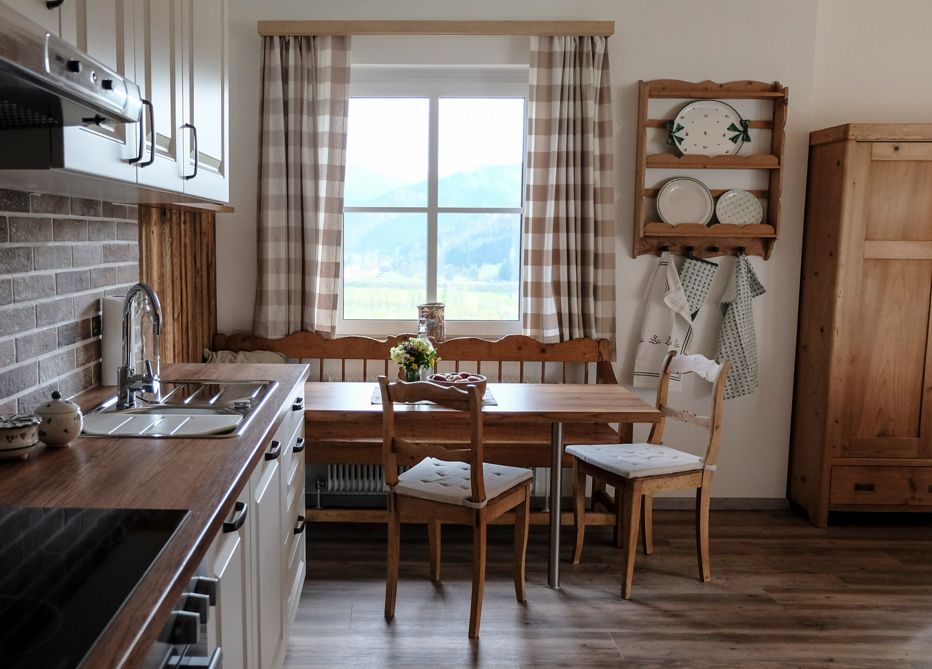 Gemütliche Küche mit Holzmöbeln und Blick aus dem Fenster auf eine Berglandschaft.