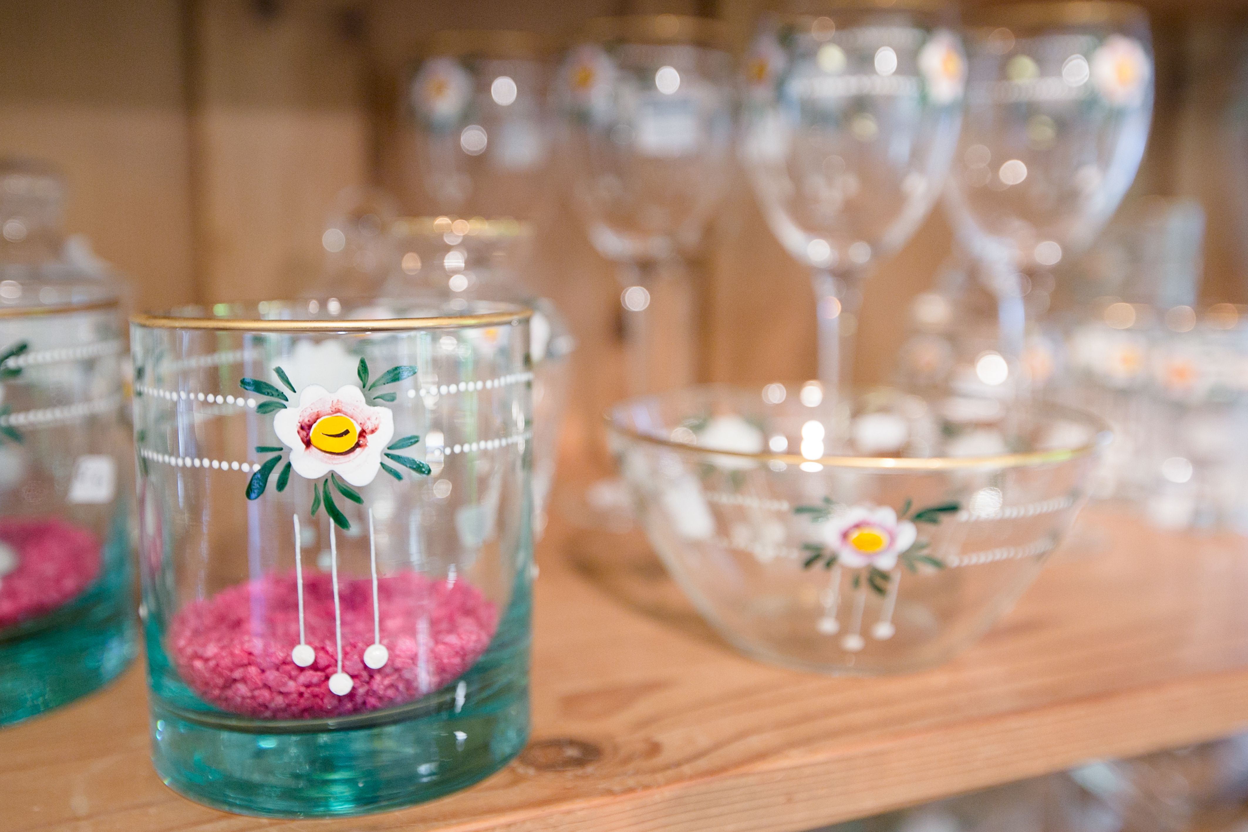 Gläser und Schalen mit Blumenmotiven auf einem Holzregal.