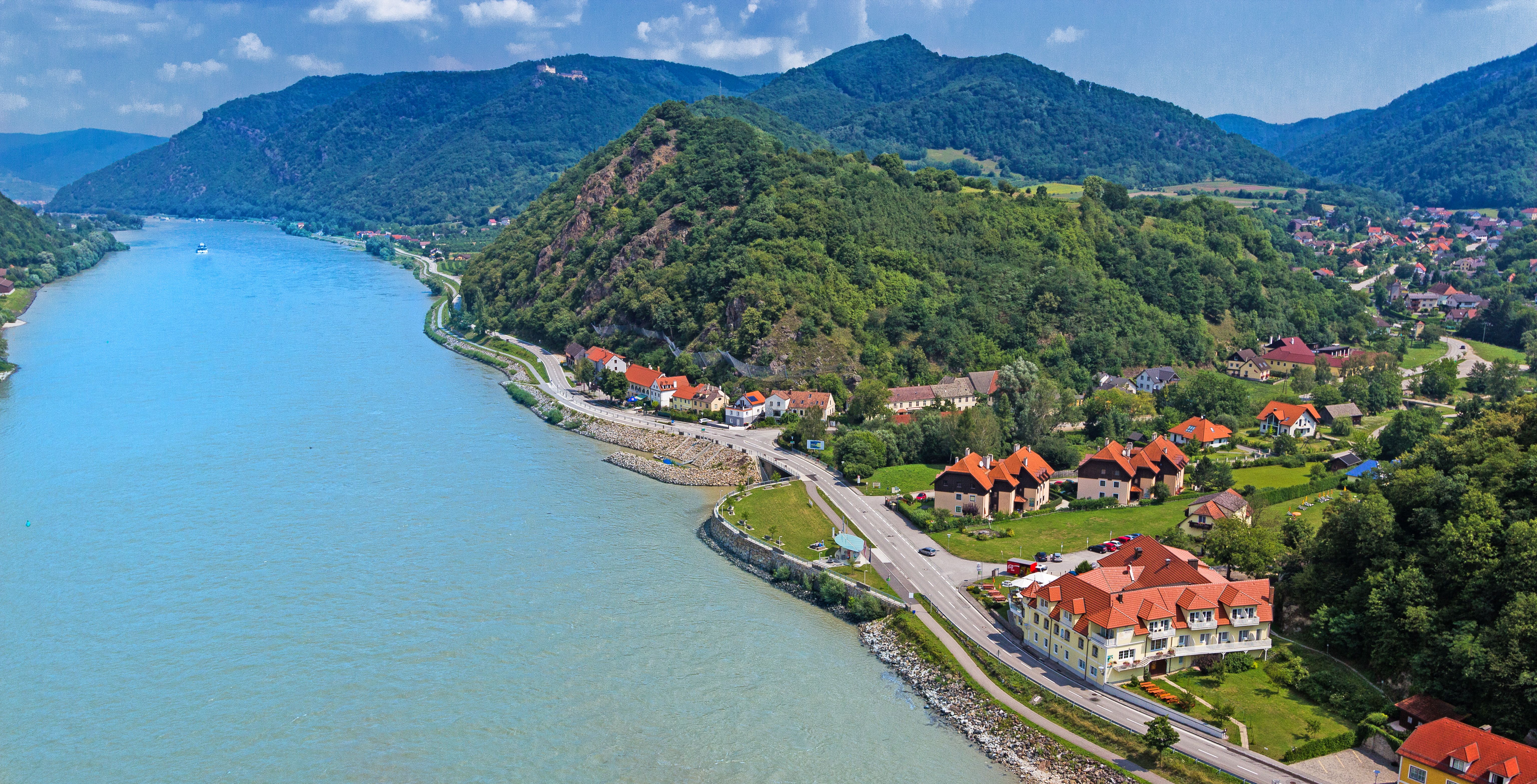 Luftaufnahme der Wachau mit Donau, Hügeln und Gebäuden.