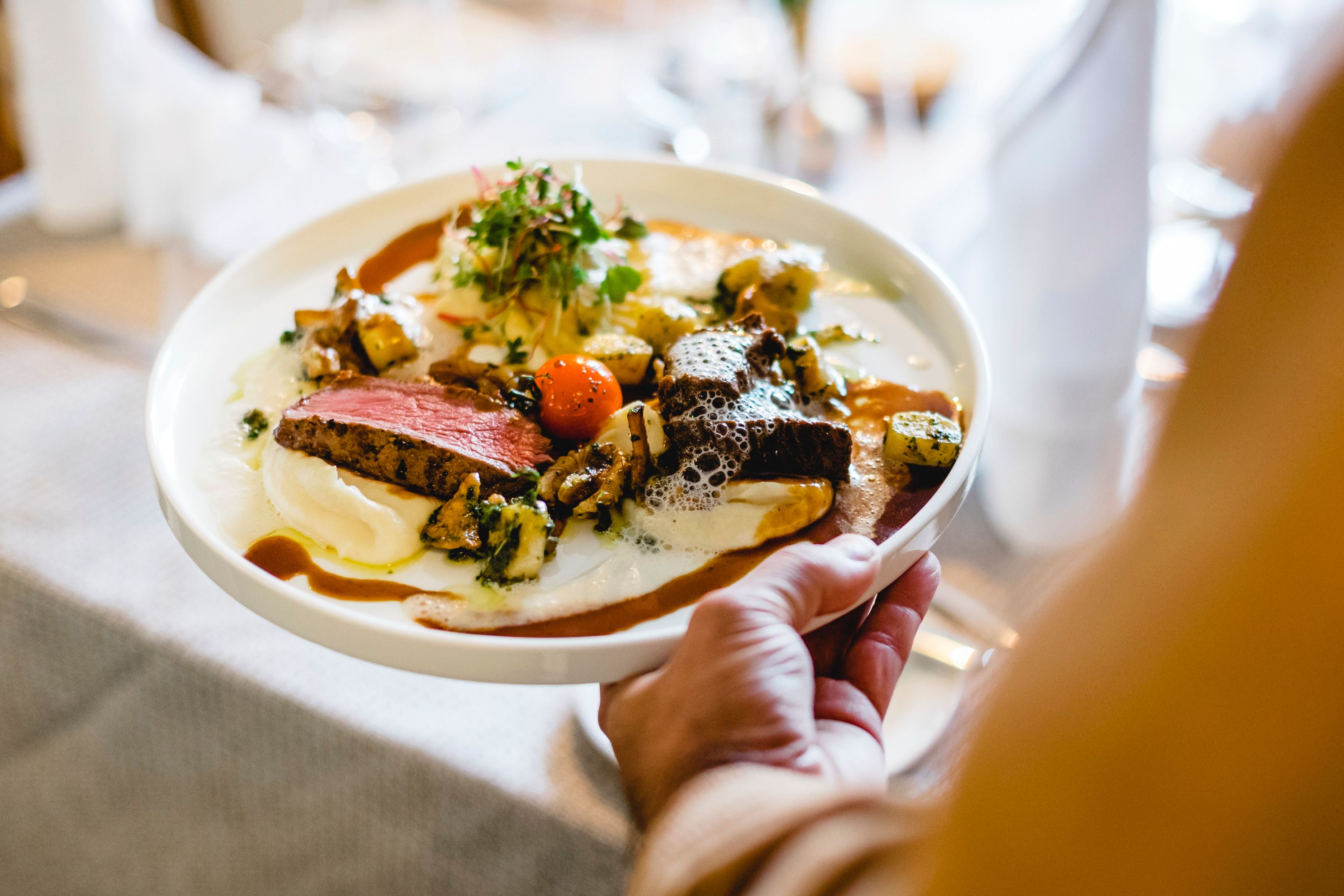 Gourmetgericht mit Hirschfleisch, Karfiolcreme und Walnuss-Gnocchi auf einem Teller.