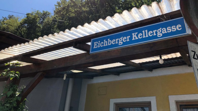 Sign with the inscription 'Eichberger Kellergasse' on a building with a corrugated iron roof.