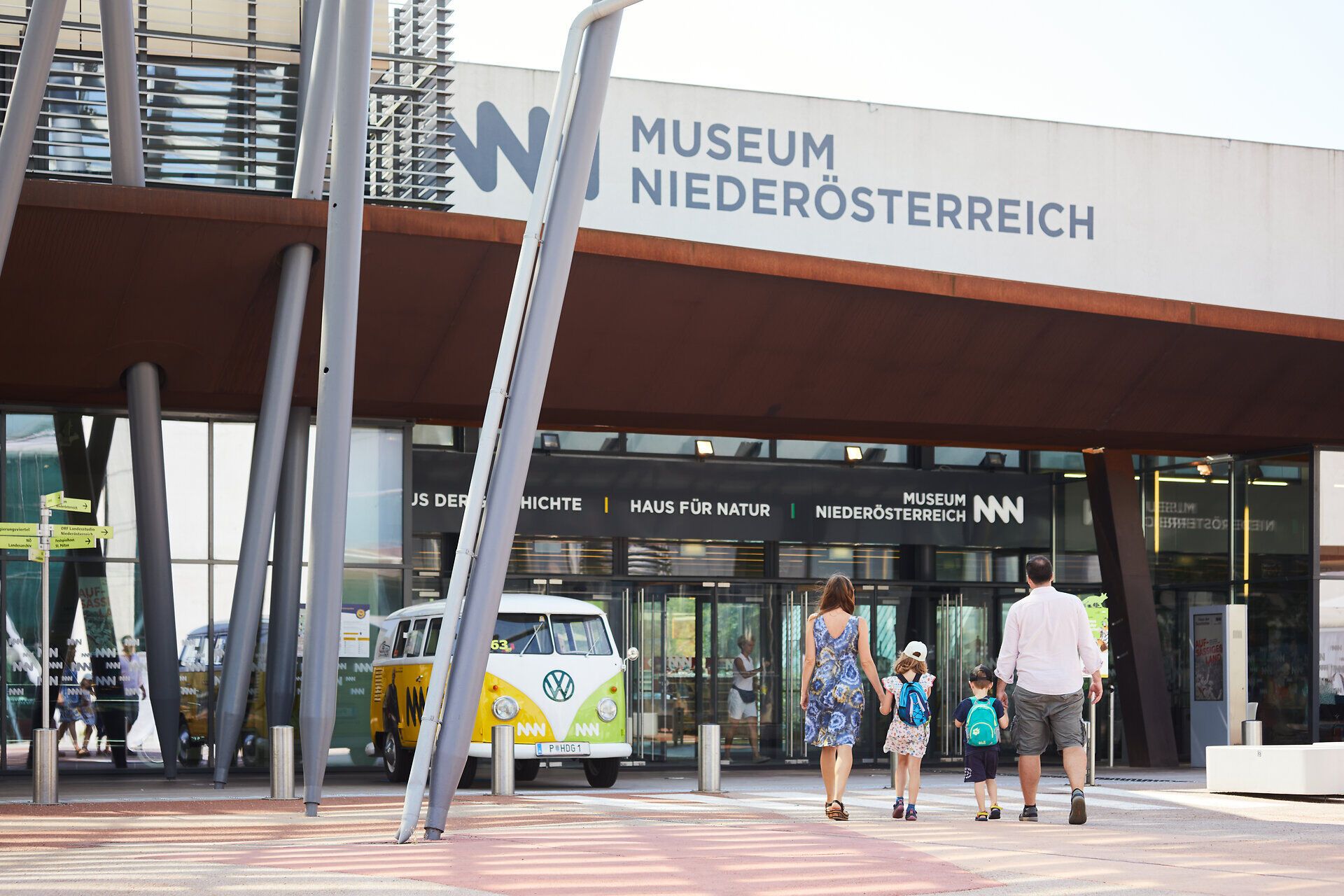 Familien genießen einen sonnigen Tag vor dem modernen Museum, das mit seiner beeindruckenden Architektur begeistert. Die fröhlichen Kinder strahlen vor Freude, während sie mit ihren Eltern in die Welt der Kunst und Kultur eintauchen.