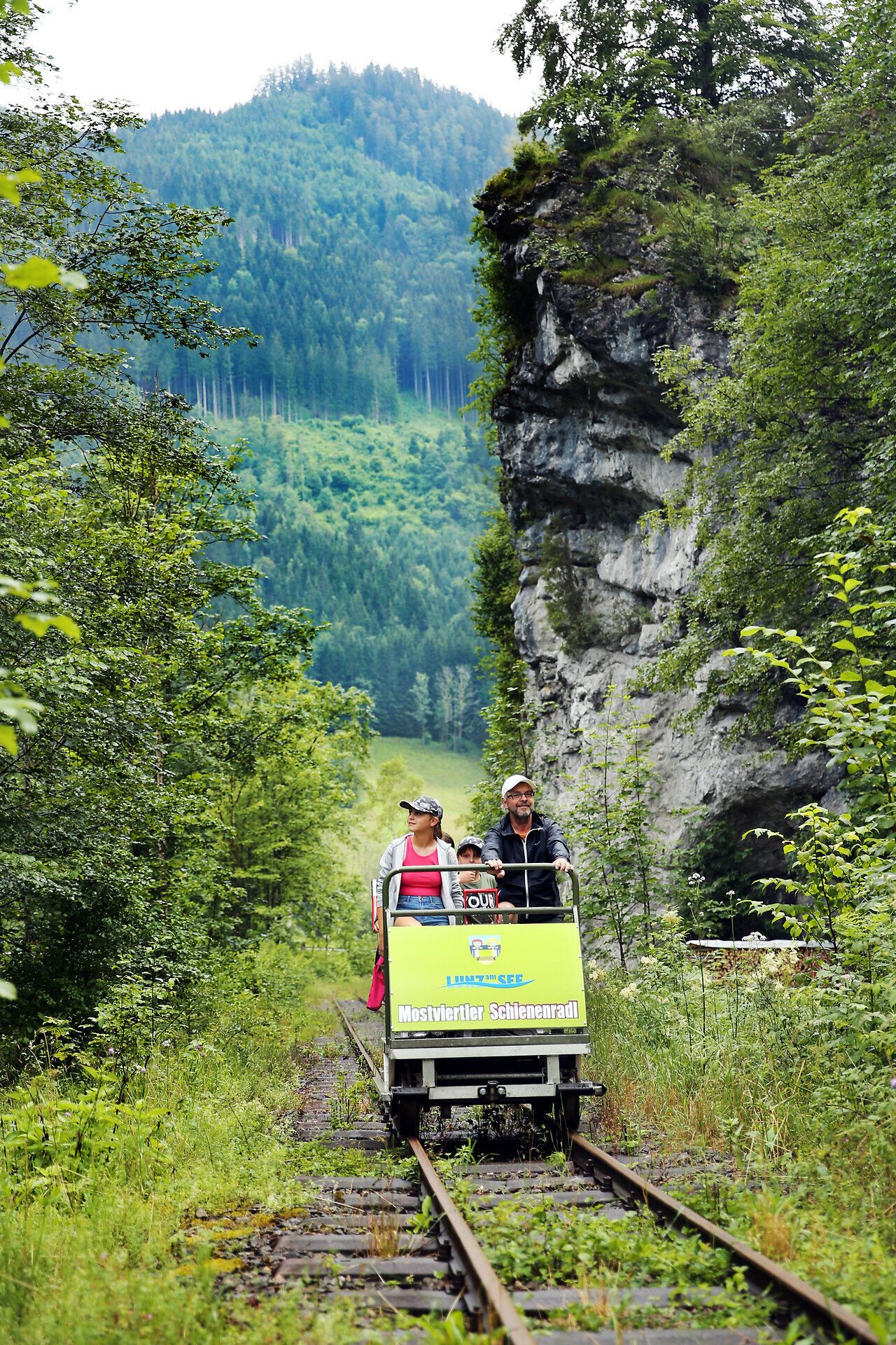 Mit einem fröhlichen Lachen gleiten die Fahrgäste auf den Schienen durch die malerische Landschaft. Umgeben von üppigem Grün und majestätischen Bergen, erleben sie die Freiheit der Natur auf eine ganz besondere Art. Diese einzigartige Fahrt verspricht unvergessliche Momente und atemberaubende Ausblicke.