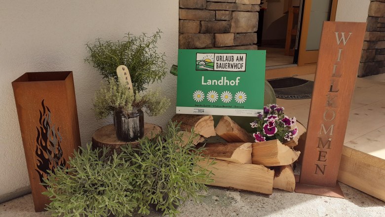 Eingangsbereich, © Maria Harrauer Eingangsbereich mit Holzscheiten und einem Willkommensschild.