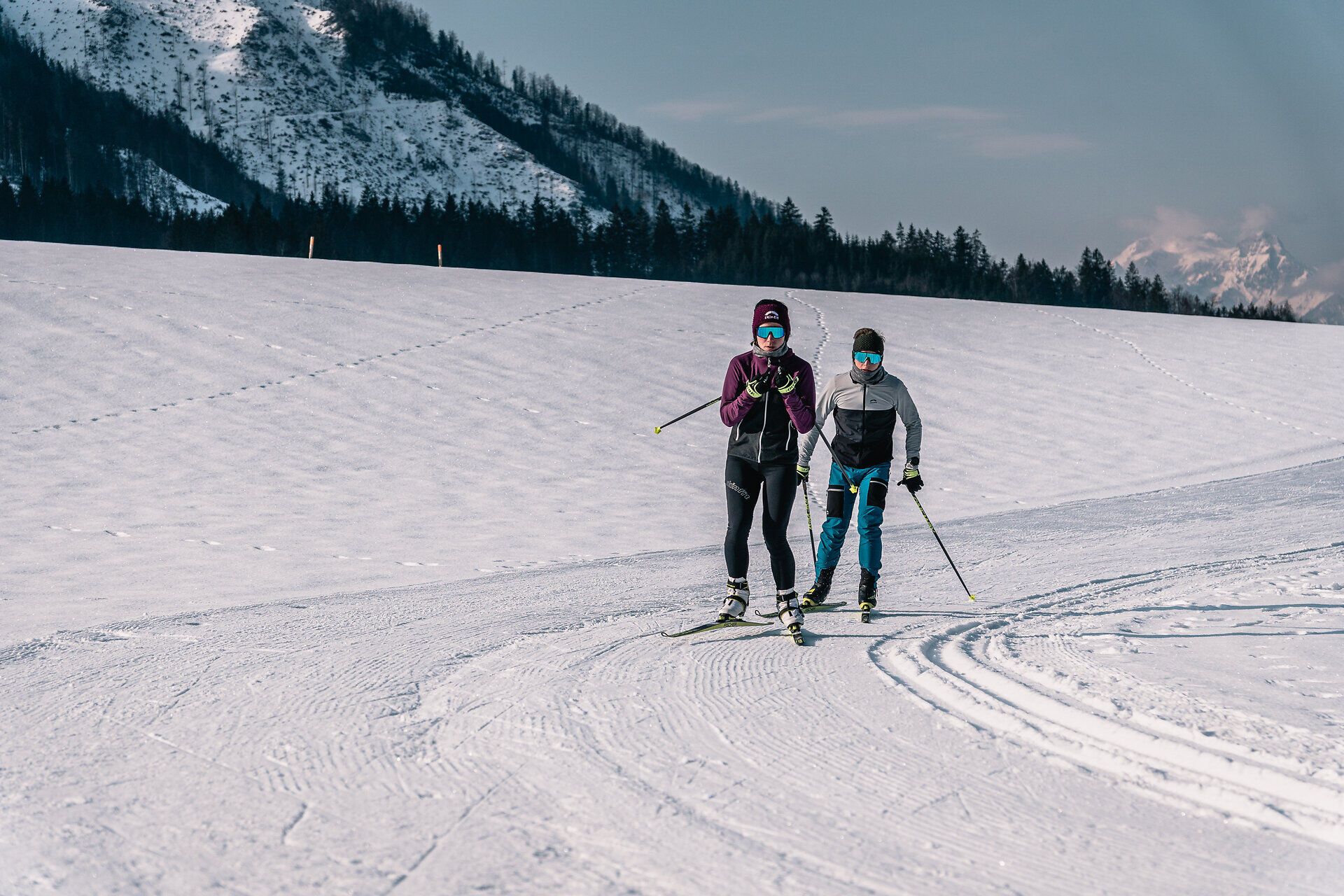Zwei begeisterte Langläufer gleiten über die schneebedeckten Loipen, umgeben von der majestätischen Kulisse der Ybbstaler Alpen. Die klare Winterluft und die glitzernde Schneedecke schaffen eine perfekte Atmosphäre für einen aktiven Urlaub in der Natur. Hier wird der Winter zum Erlebnis für alle Sportbegeisterten.