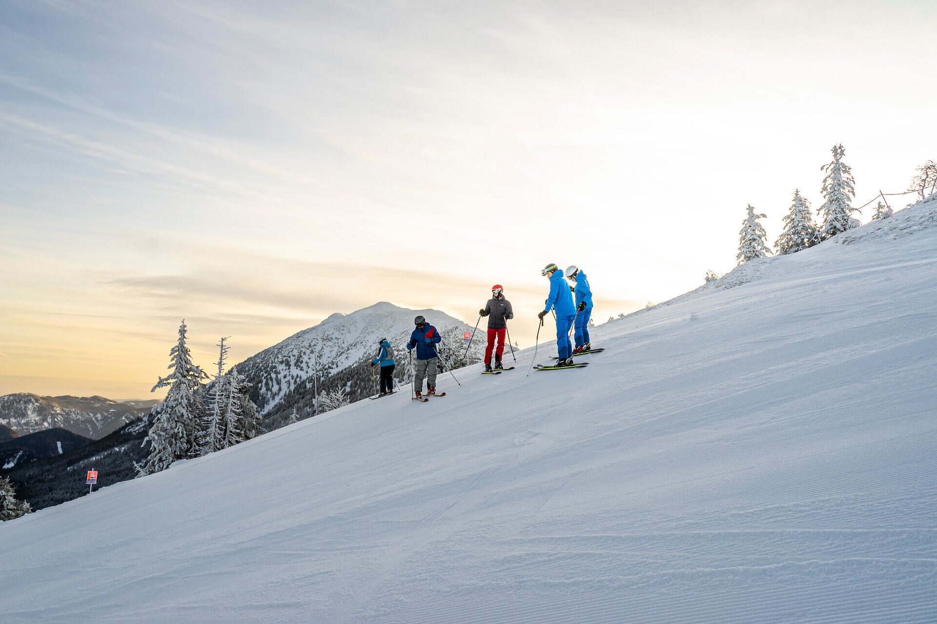 Die frische Morgenluft erfüllt die Skifahrer mit Energie, während sie sich auf die perfekt präparierten Pisten begeben. Umgeben von schneebedeckten Tannen und der majestätischen Kulisse der Ybbstaler Alpen, erleben sie den Winter in seiner schönsten Form.