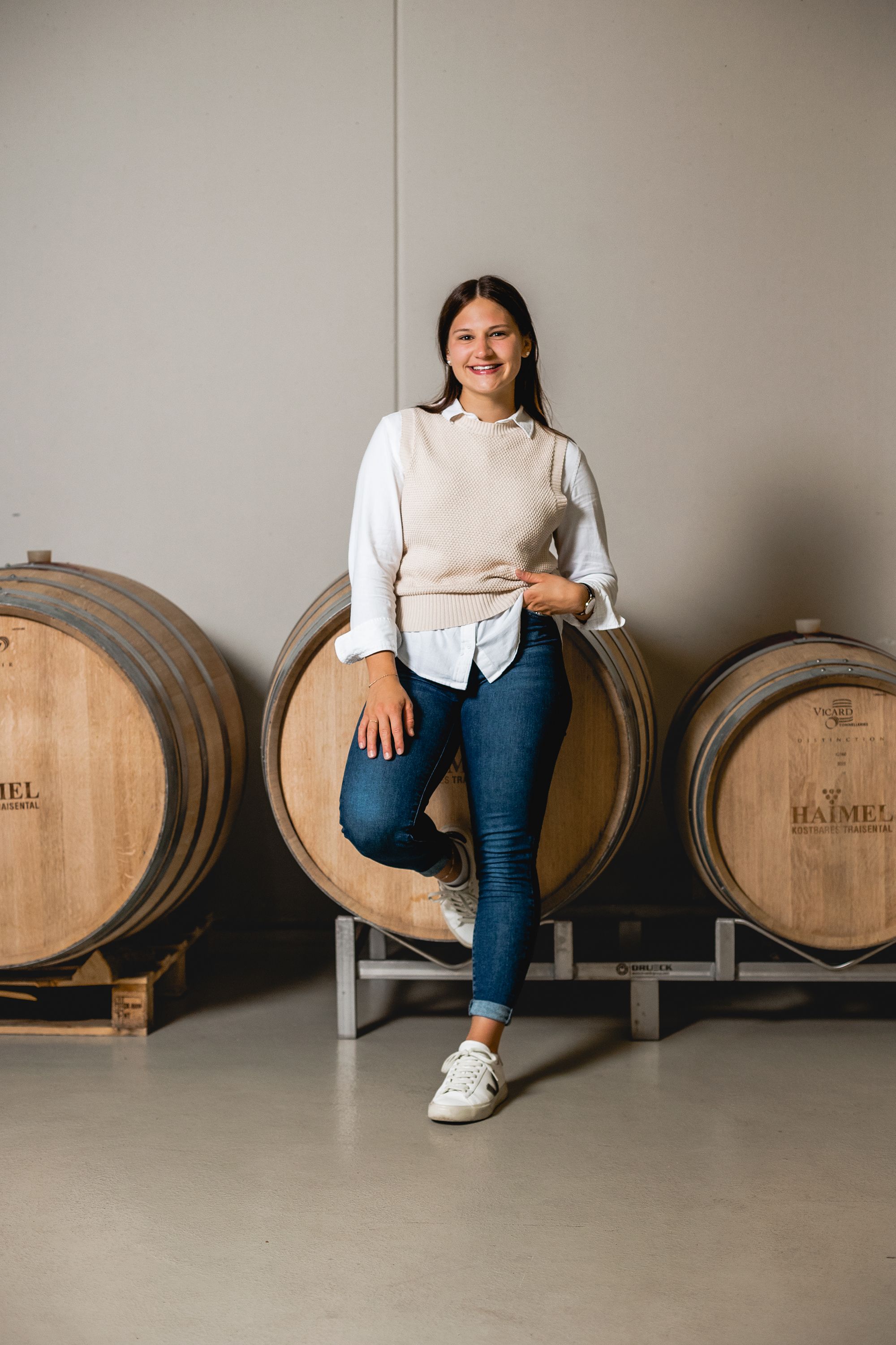 Eine Frau lehnt lächelnd an einem Weinfass im Weingut Haimel.