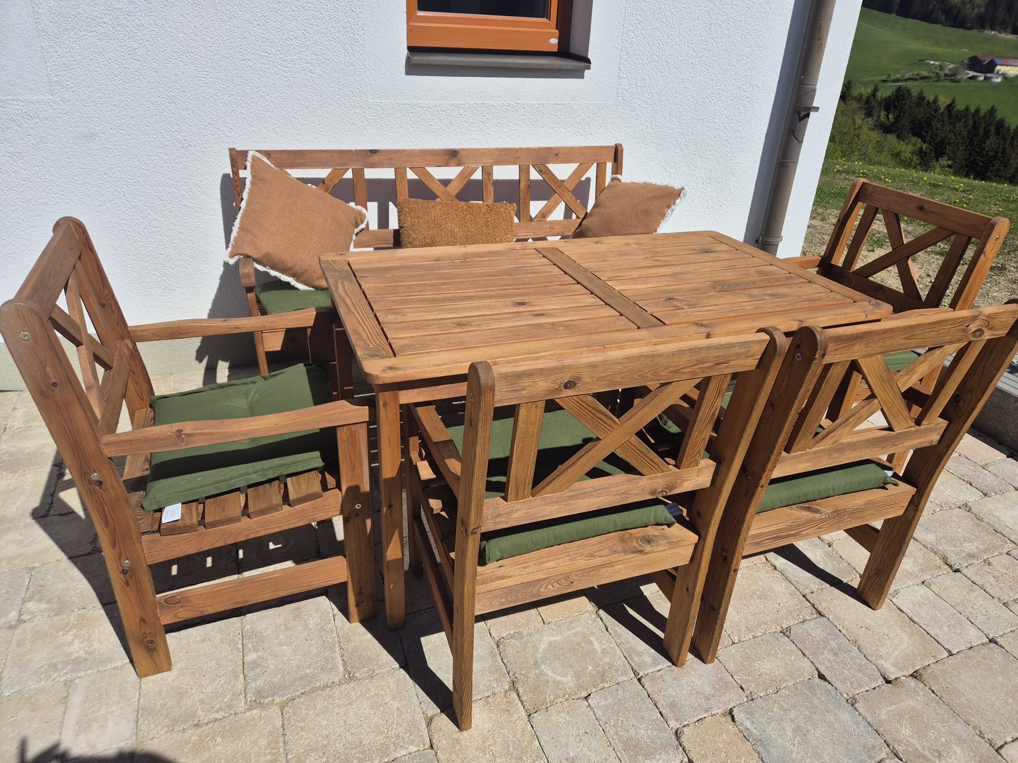 Holz-Gartenmöbel-Set mit Tisch, Stühlen und Bank auf einer Terrasse.