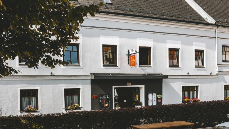 Ein traditionelles Wirtshaus in Mank mit wei&szlig;en W&auml;nden und Blumenk&auml;sten an den Fenstern.