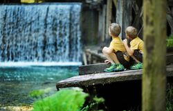 Zwei Kinder sitzen am Ufer eines glitzernden Baches und beobachten fasziniert das plätschernde Wasser, das über die Steine fließt. Umgeben von üppigem Grün und dem sanften Rauschen der Natur, erleben sie einen unvergesslichen Moment der Kindheit in der idyllischen Landschaft. Hier im Mendlingtal wird der Familienurlaub zum Abenteuer voller Entdeckungen.