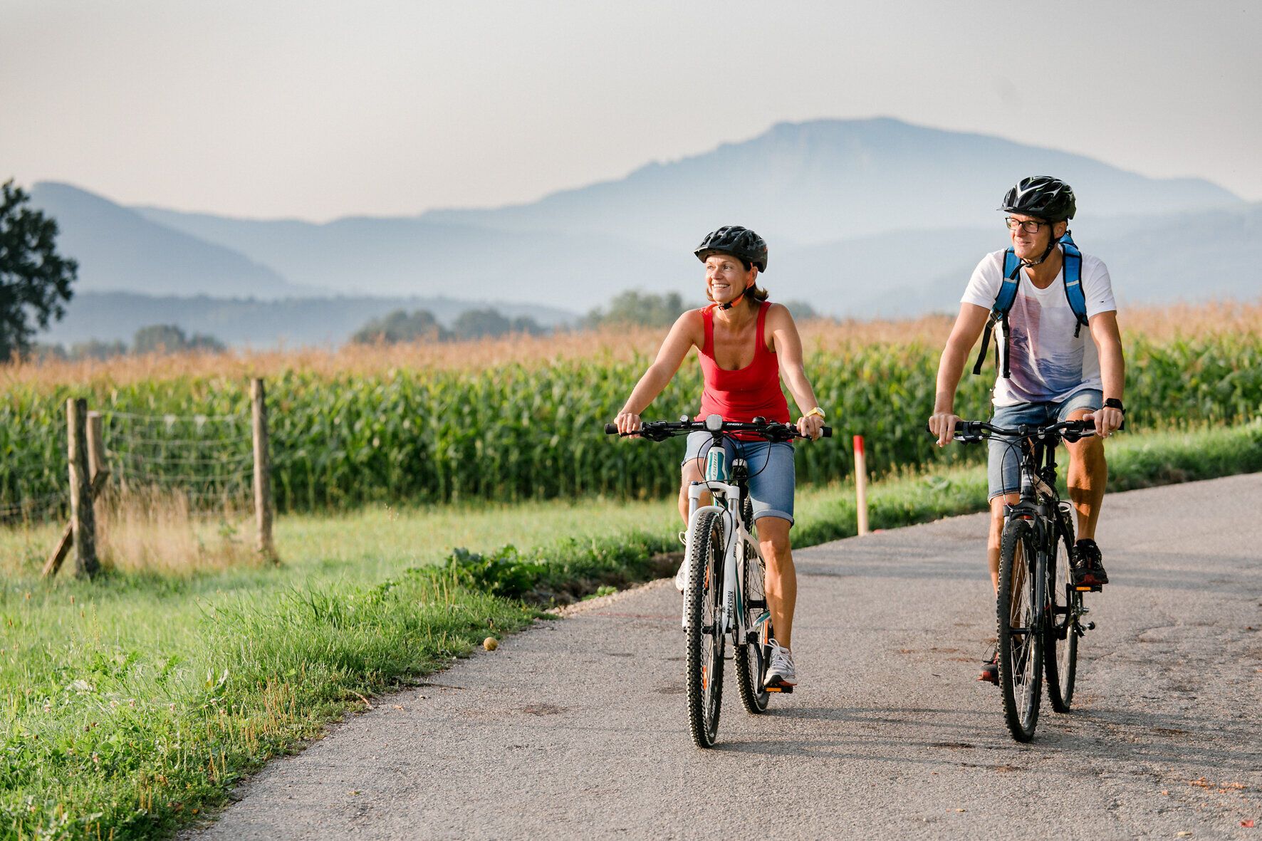 Ein Paar genießt die frische Bergluft, während sie auf ihren Fahrrädern den malerischen Erlauftalradweg entlangfahren. Umgeben von üppigen Wiesen und sanften Hügeln strahlt die Landschaft eine einladende Ruhe aus, die zum Verweilen einlädt.