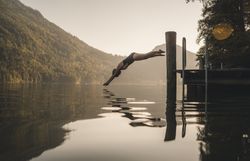 Frau springt vom Steg kopfüber in einen See