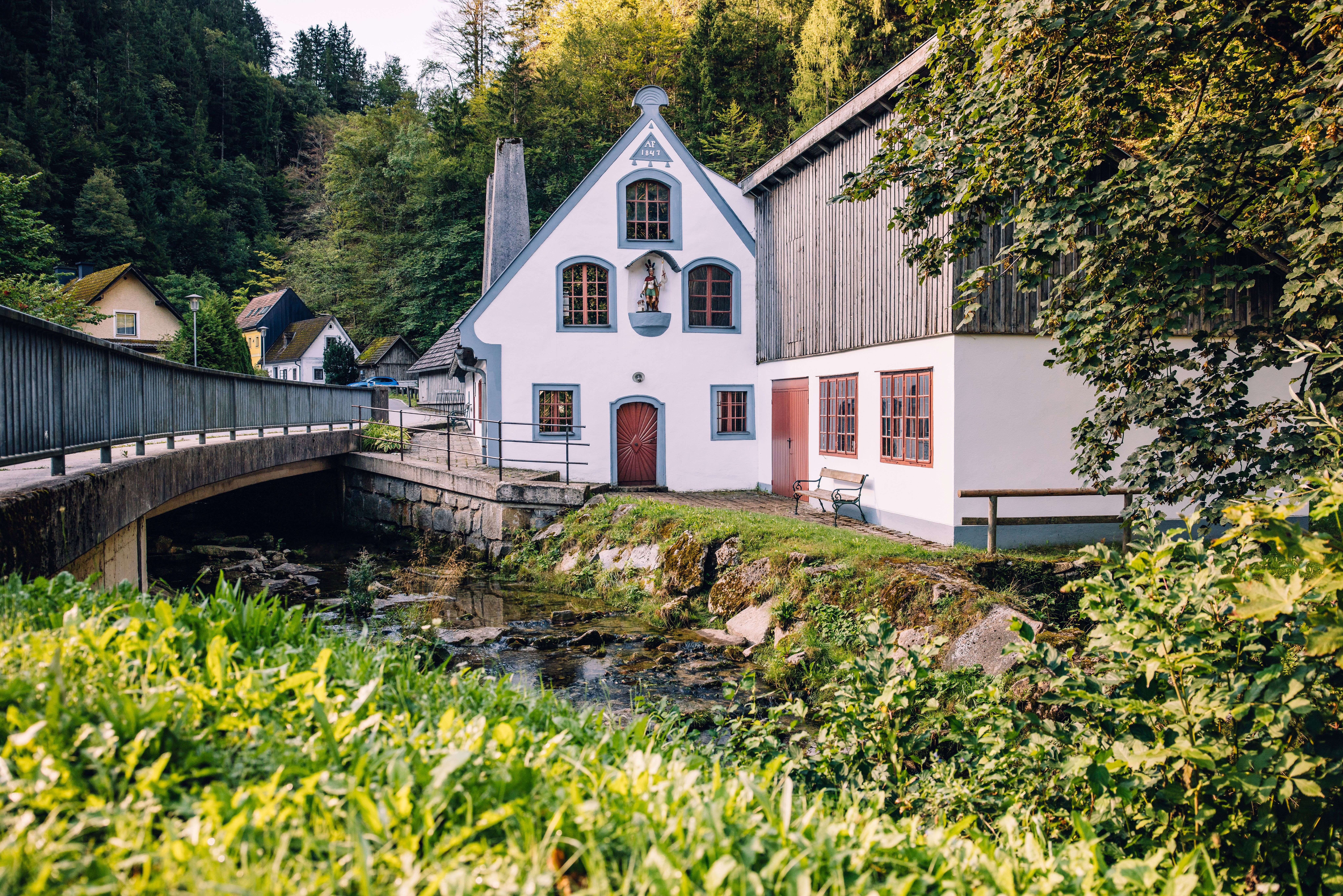 Fahrngruber Hammer in Ybbsitz mit historischem Schmiedegebäude und Brücke über den Bach, umgeben von grüner Natur.