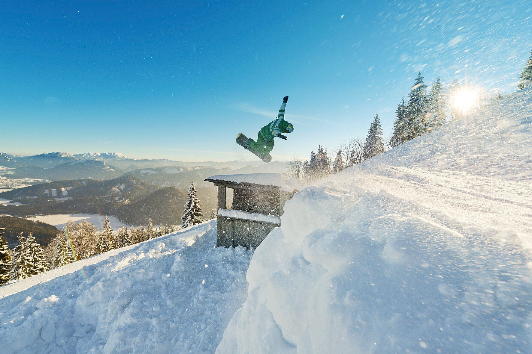 Ein Snowboarder schwebt durch die glitzernde Winterlandschaft, während die Sonne sanft über den schneebedeckten Bergen aufgeht. Die frische, kalte Luft und der weiche Schnee schaffen eine perfekte Kulisse für Abenteuer und Spaß im Freien.