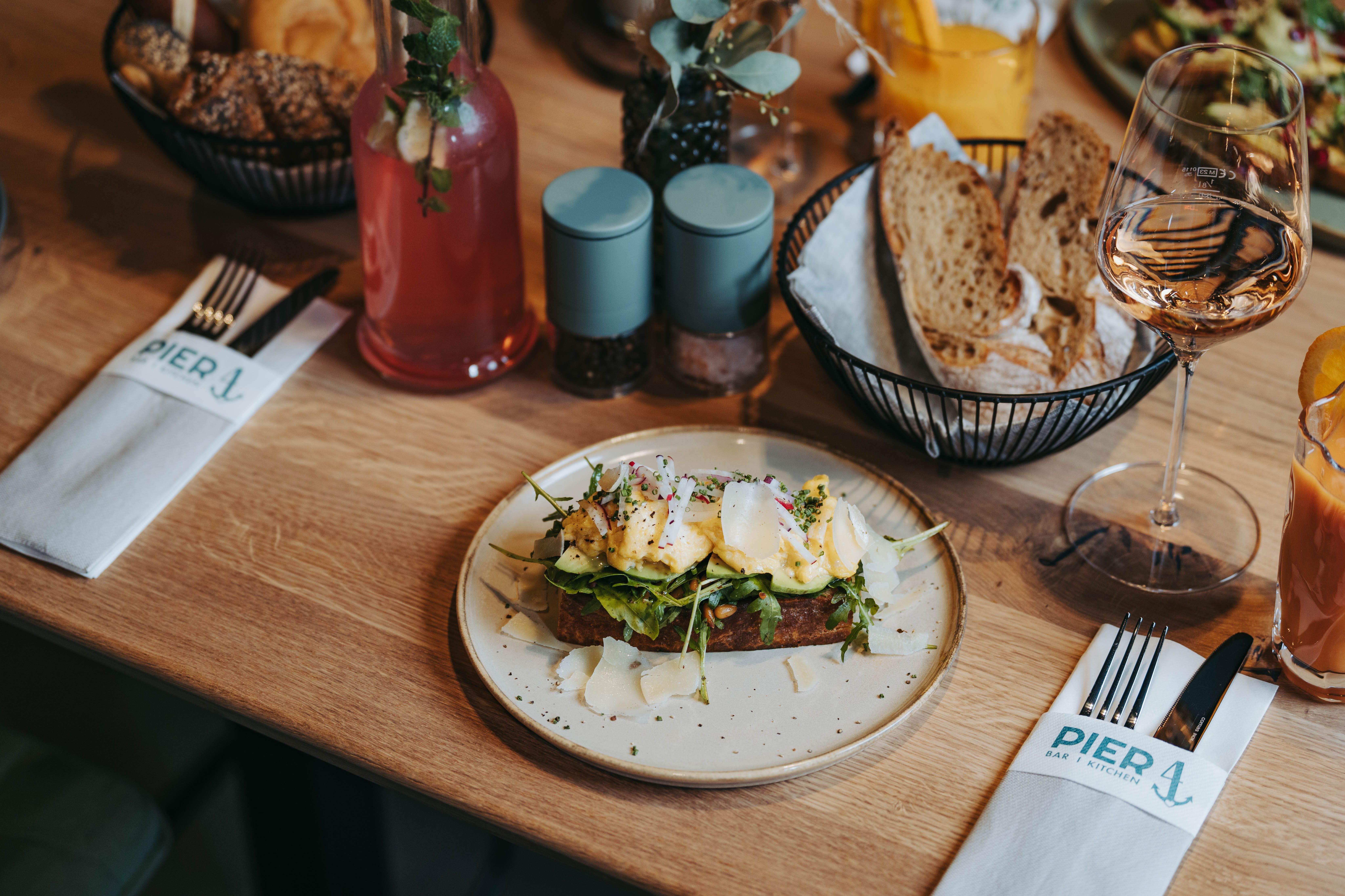 Ein gedeckter Tisch mit einem belegten Brot, Getränken und Besteck im Restaurant Pier 4.