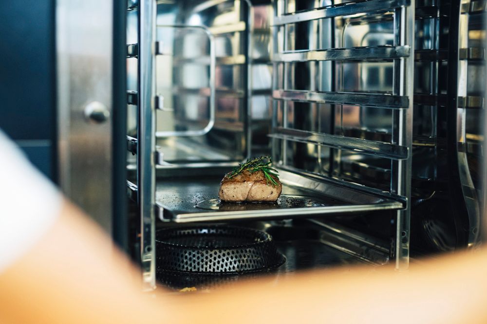 Ein Stück Fleisch mit Kräutern in einem professionellen Ofen.