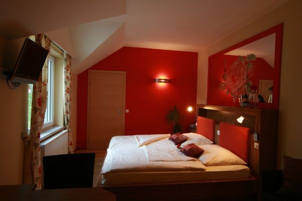 Gemütliches Schlafzimmer mit roter Wand und Doppelbett.