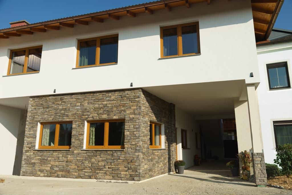 Moderne Hausfassade mit weißem Putz und Natursteinverkleidung.