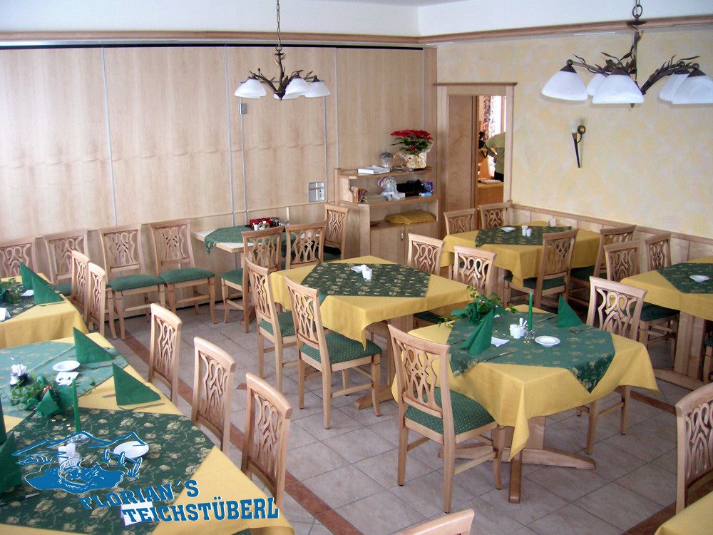 Innenansicht eines Restaurants mit Holzmöbeln und gelb-grünen Tischdecken.