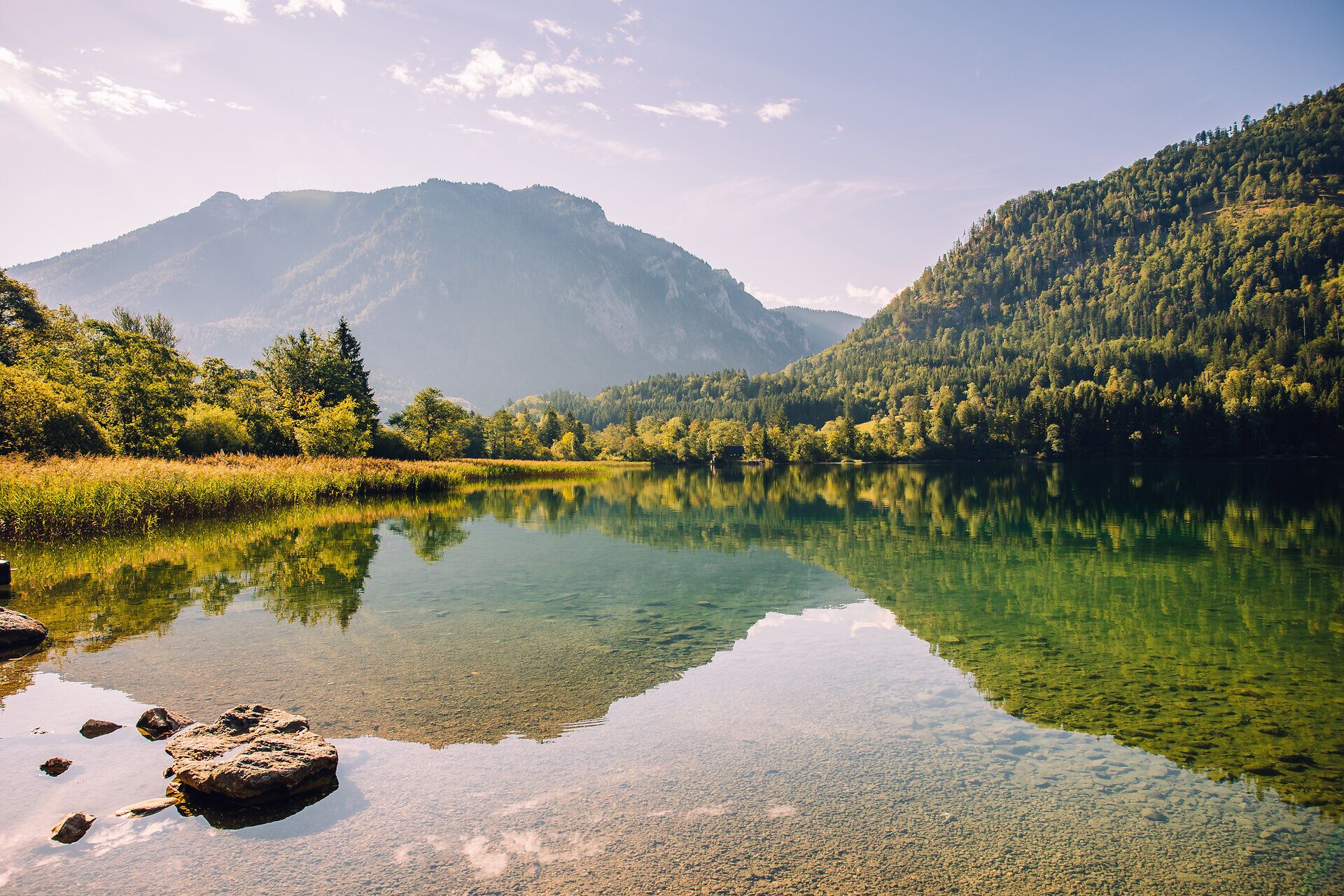 Blick auf den klaren Lunzer See mit Spiegelungen der umliegenden Berge und bewaldeten Hänge in den Ybbstaler Alpen.