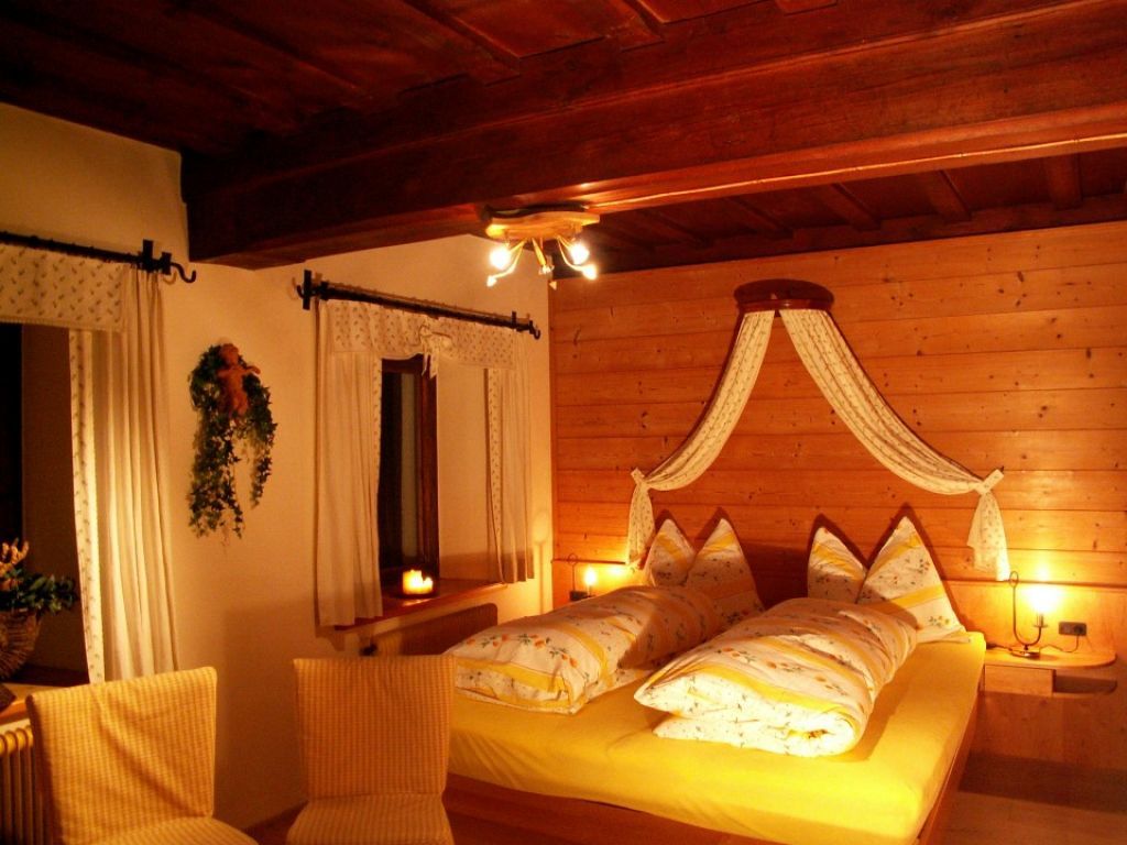 Gemütliches Schlafzimmer mit Holzwänden und gelber Bettwäsche.