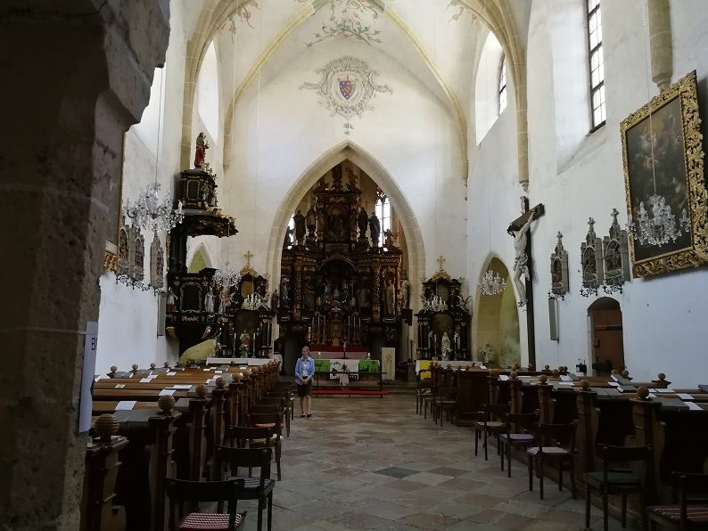 Innenansicht einer Wallfahrtskirche mit Altar, Bänken und religiösen Kunstwerken.