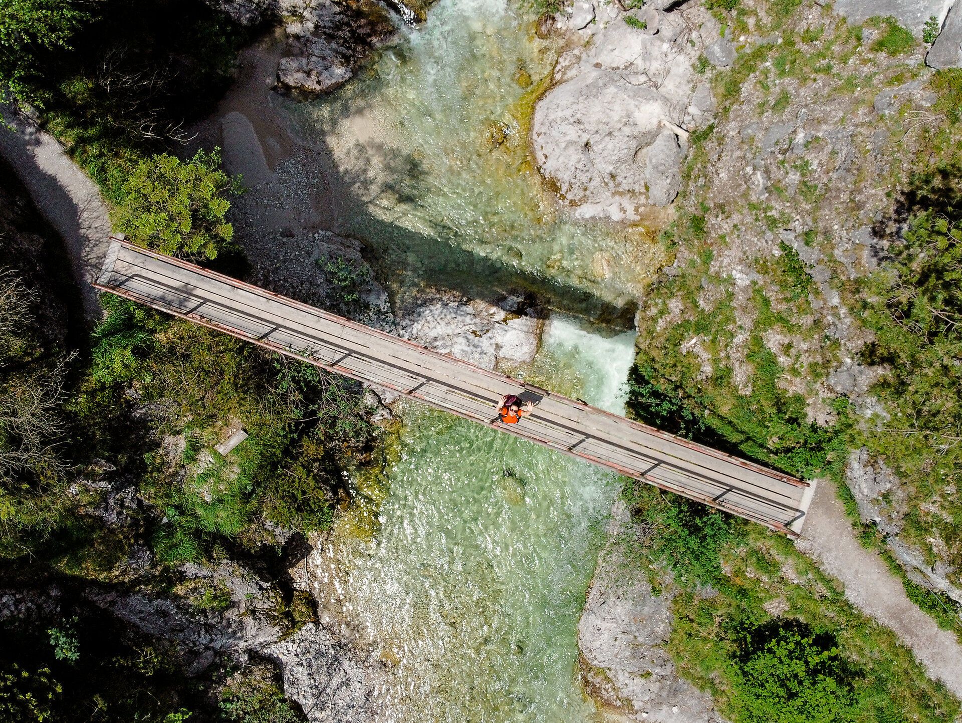 Ein malerischer Holzsteg führt über das glitzernde Wasser, umgeben von üppigem Grün und majestätischen Felsen. Die frische Bergluft und das sanfte Plätschern des Wassers laden zu einer Auszeit in der Natur ein. Hier, im Herzen des Naturparks, entfaltet sich die Schönheit der alpinen Landschaft in voller Pracht.