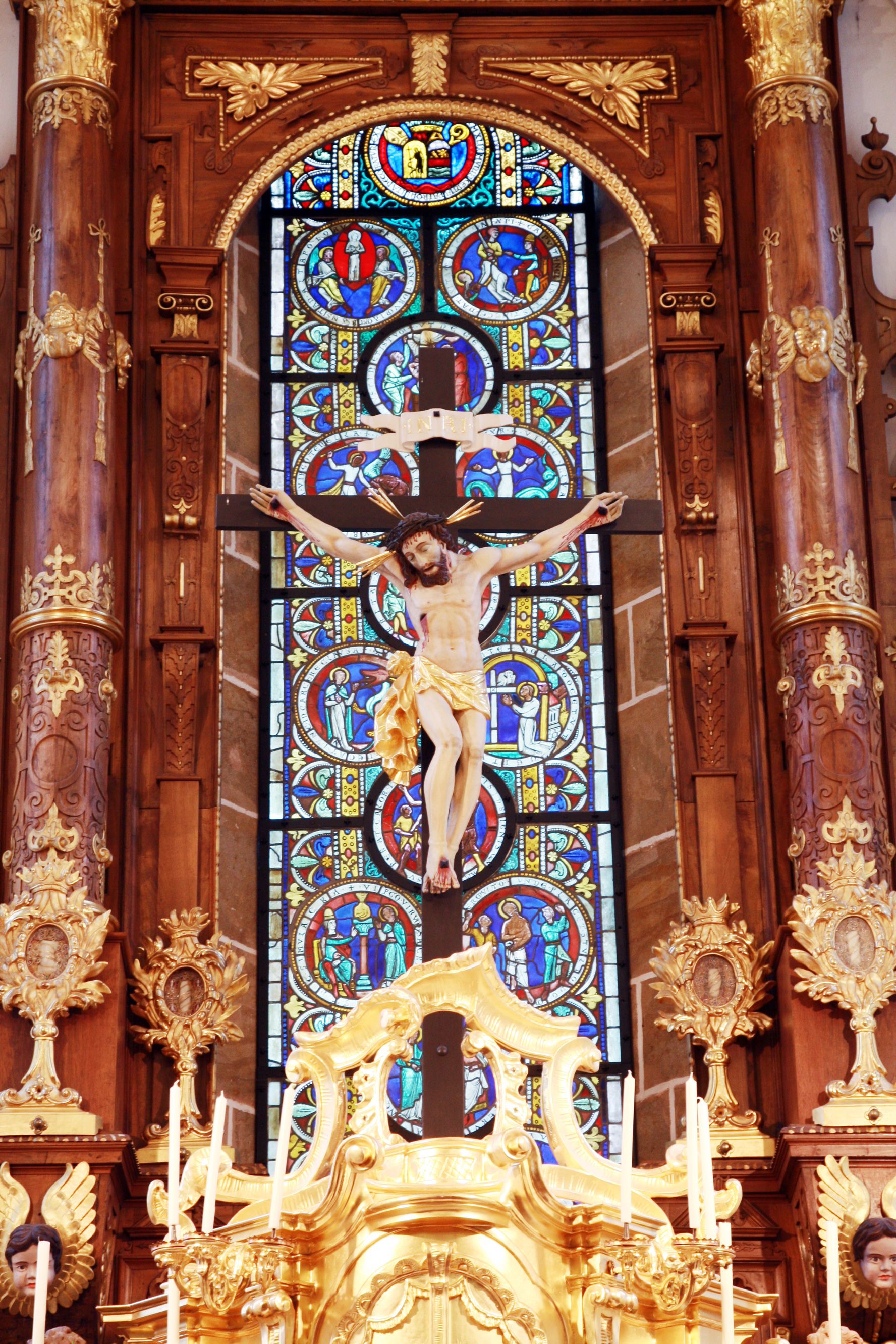 Kruzifix vor einem bunten Kirchenfenster in der Stiftskirche Ardagger.