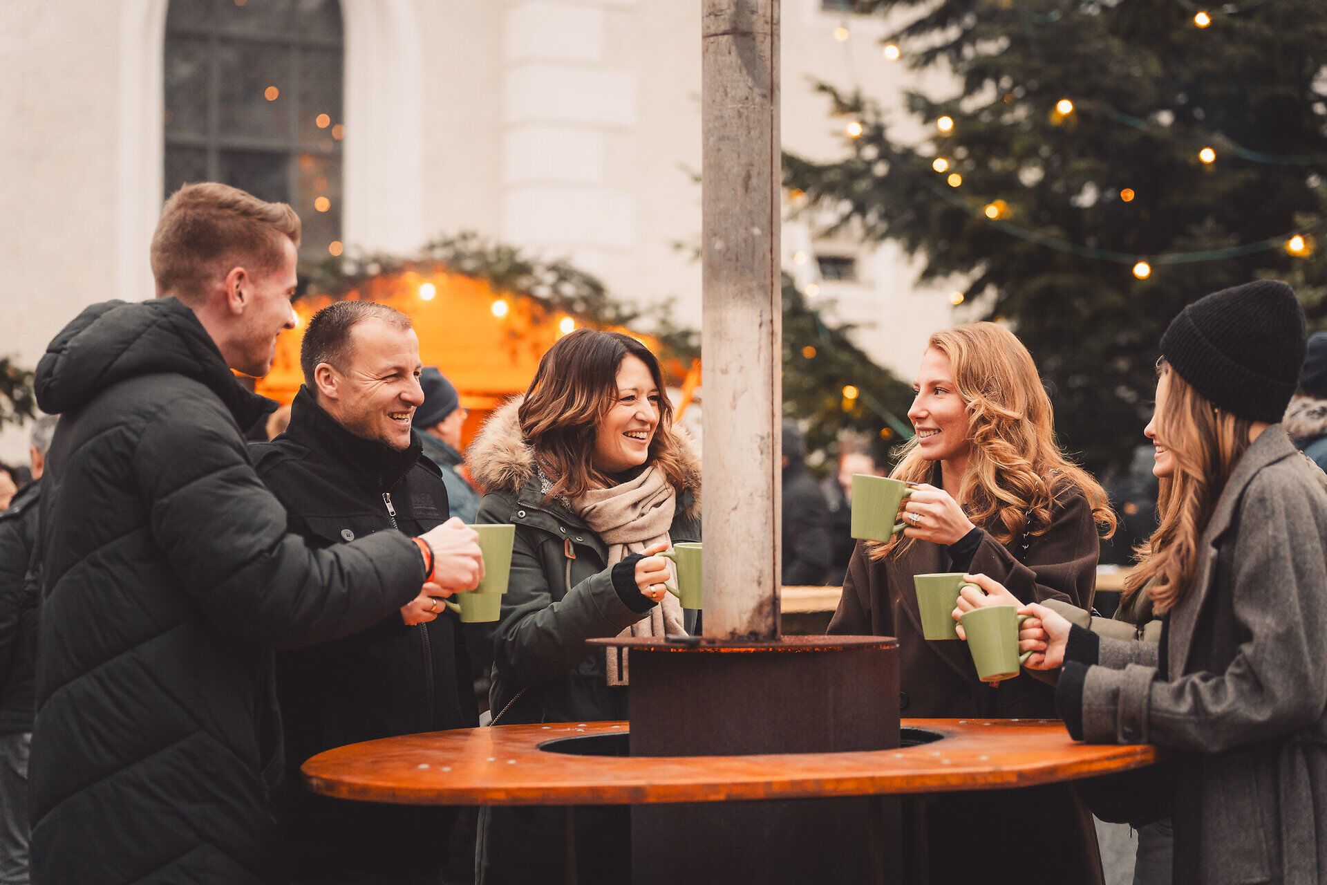 Besuchende des Adventmarkts in Ybbsitz stoßen mit Heißgetränk an.