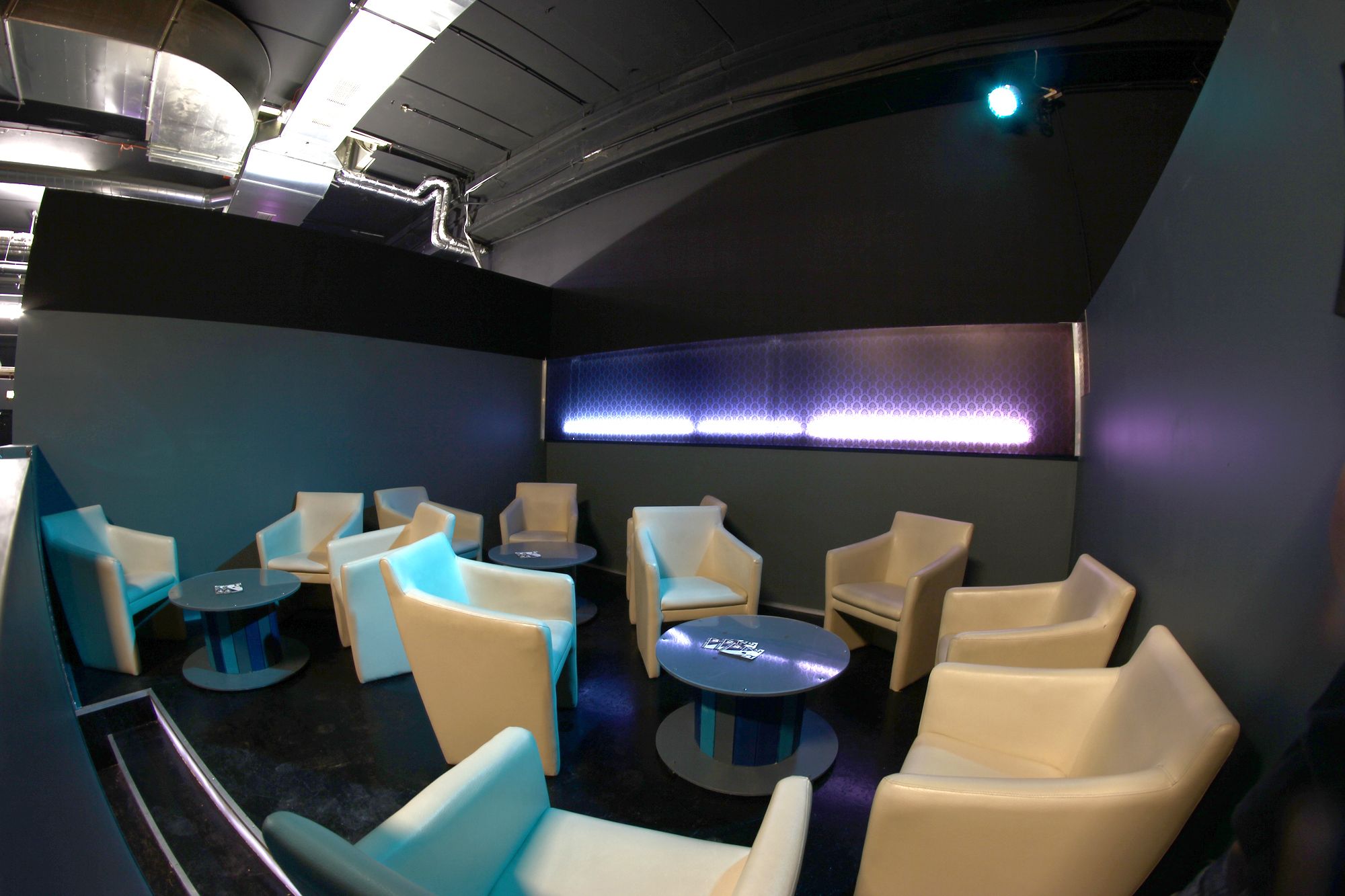 Lounge-Bereich mit beigen Sesseln und runden Tischen in einem modernen Raum.