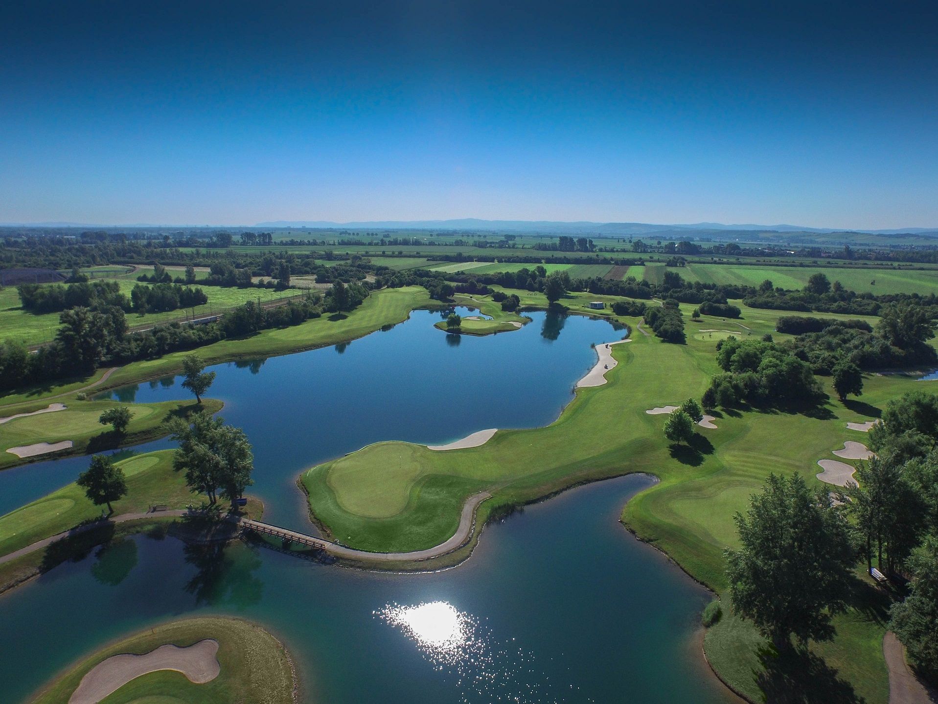 Luftaufnahme eines Golfplatzes mit Wasserhindernissen und grünen Fairways.