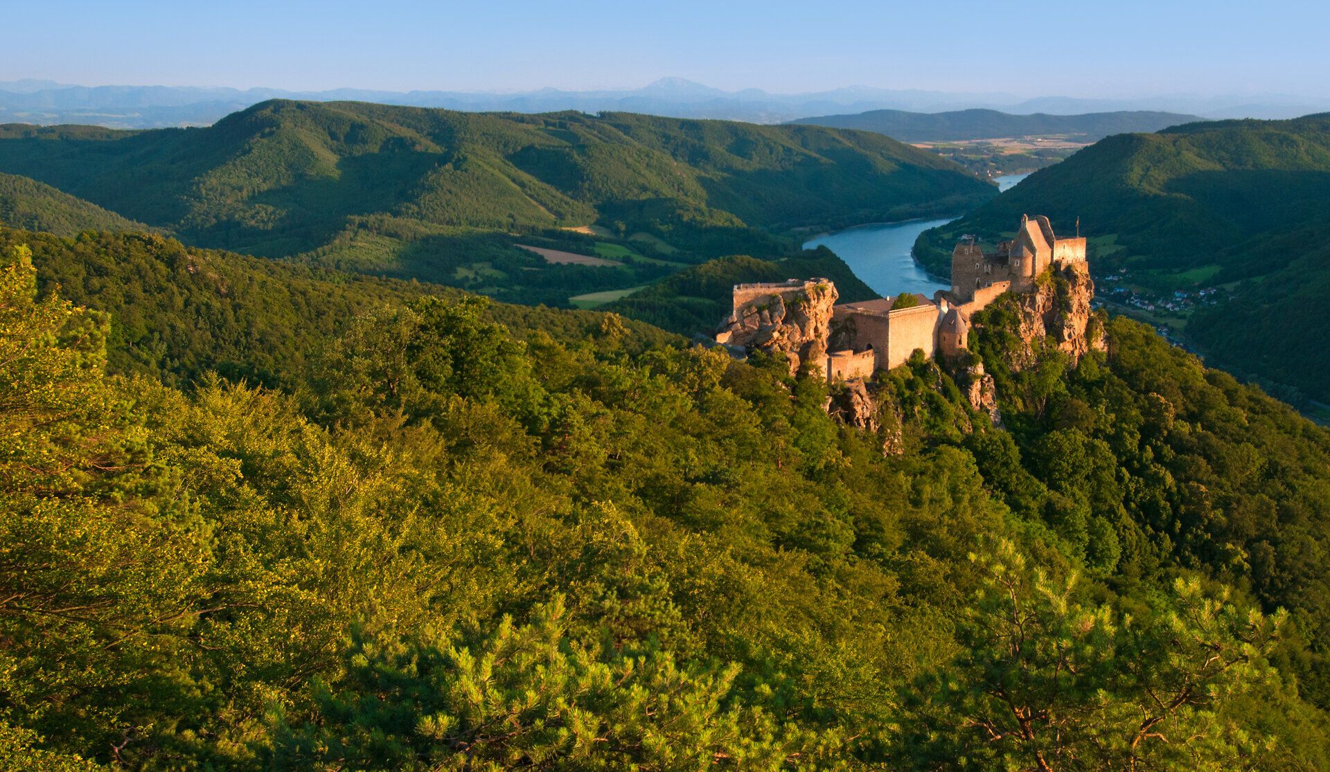 Die Ruine Aggstein thront majestätisch über der Donau und bietet einen atemberaubenden Blick auf die umliegenden grünen Hügel. Im Sommer erstrahlt die Landschaft in voller Pracht und lädt zu unvergesslichen Erlebnissen in der Natur ein.