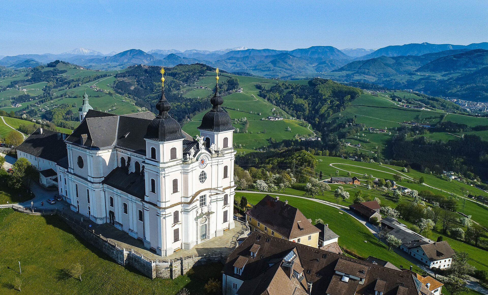 Die Basilika Sonntagberg thront majestätisch über der blühenden Landschaft, umgeben von sanften Hügeln und blühenden Birnbäumen. Im Frühling erstrahlt die Umgebung in einem Meer aus Farben, während die frische Luft die Sinne belebt und zu Erkundungen einlädt.