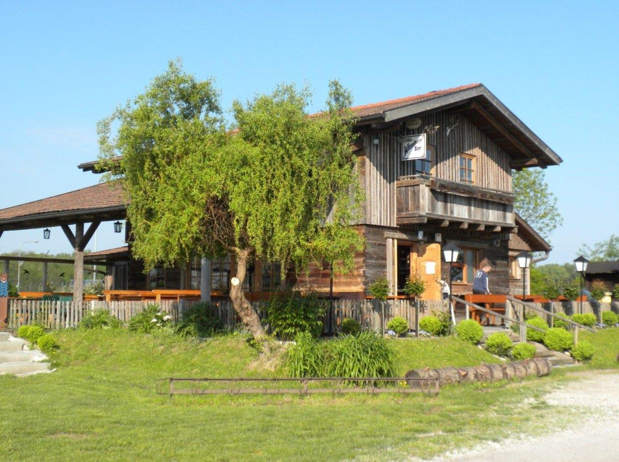 Eine rustikale Holzhütte mit Terrasse und Garten im Grünen, bei sonnigem Wetter.