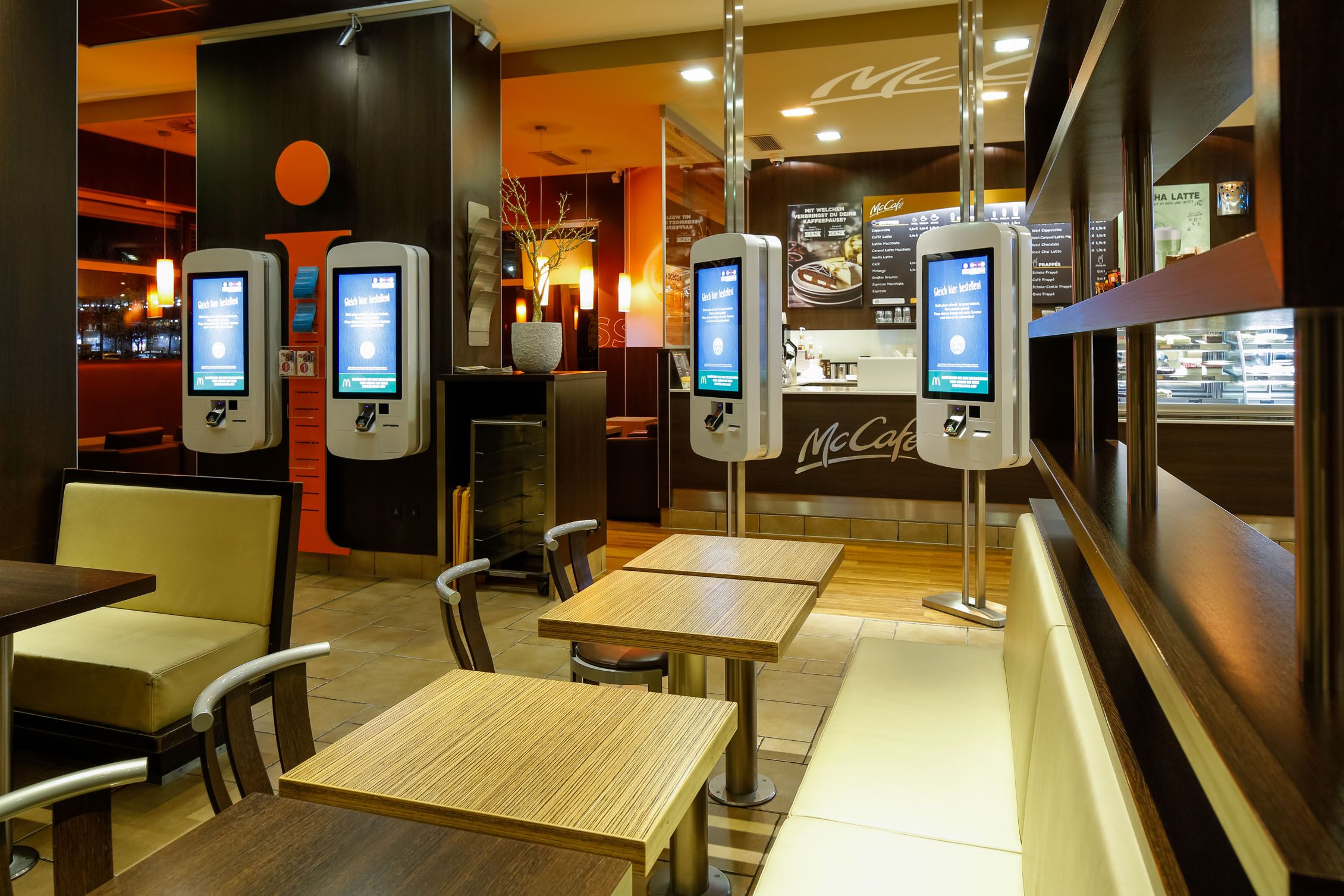 Innenansicht eines McDonald's Restaurants mit Bestellterminals und Sitzbereichen.