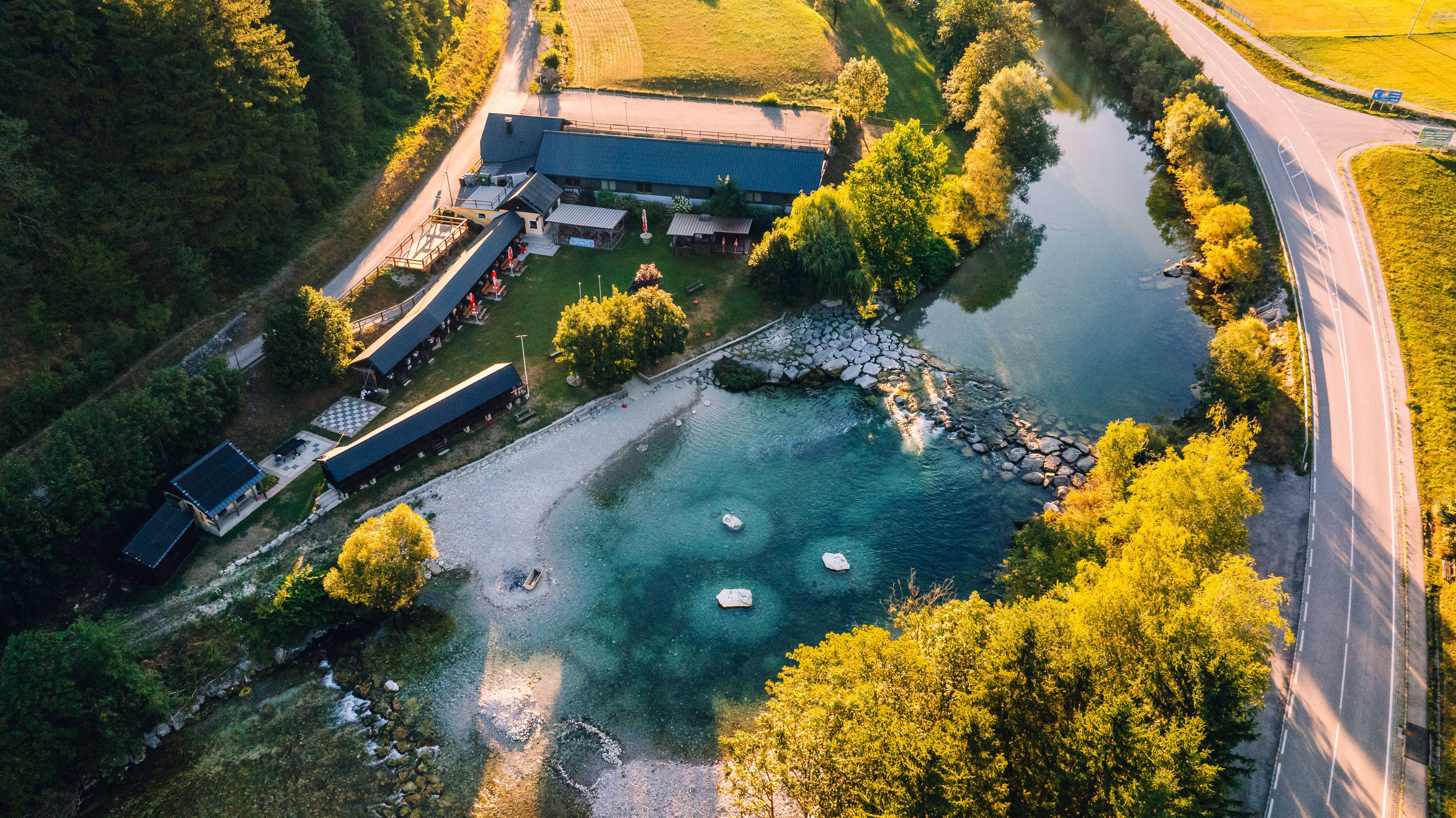 Luftaufnahme vom Strandbad Hollenstein mit türkisfarbenem Wasser der Ybbs, Uferweg, Gebäude und Straße im Abendlicht.
