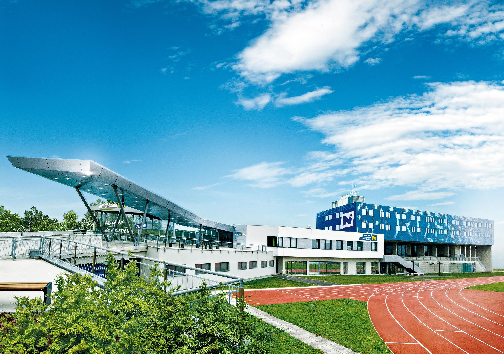 Modernes Sportzentrum mit Laufbahn und blauen Himmel.