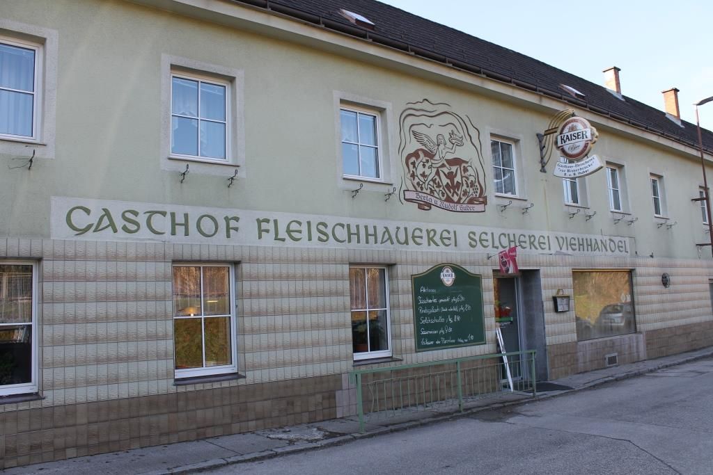 Außenansicht eines Gasthofs mit der Aufschrift 'Gasthof Fleischhauerei Selcherei Viehhandel'.