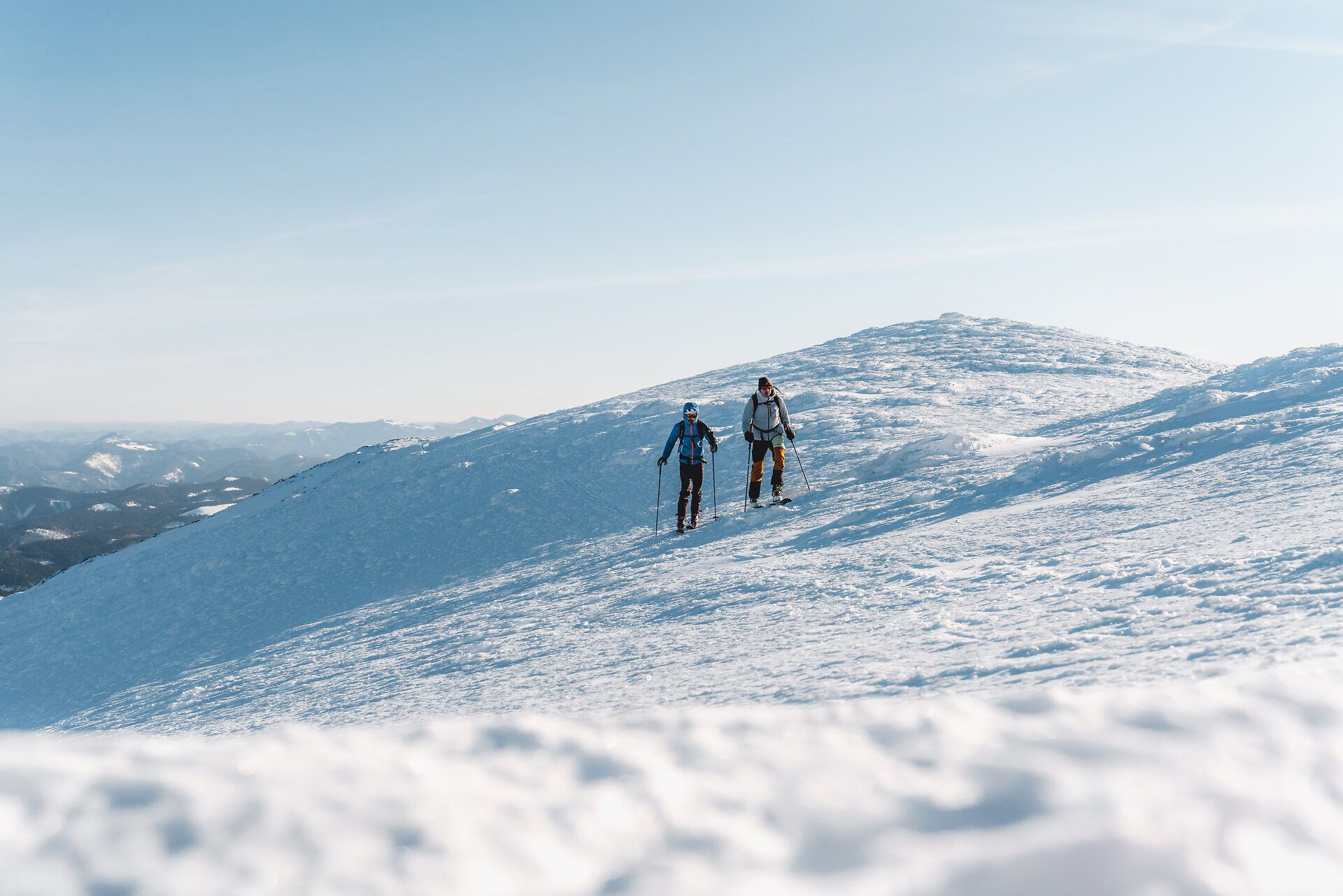 Zwei begeisterte Skitourengeher durchqueren die glitzernde Schneelandschaft des Ötschers. Die klare Winterluft und die majestätischen Berge schaffen eine unvergessliche Atmosphäre, die zum Abenteuer einlädt. Hier, wo die Natur in ihrer reinsten Form erstrahlt, wird jeder Schritt zu einem Erlebnis.