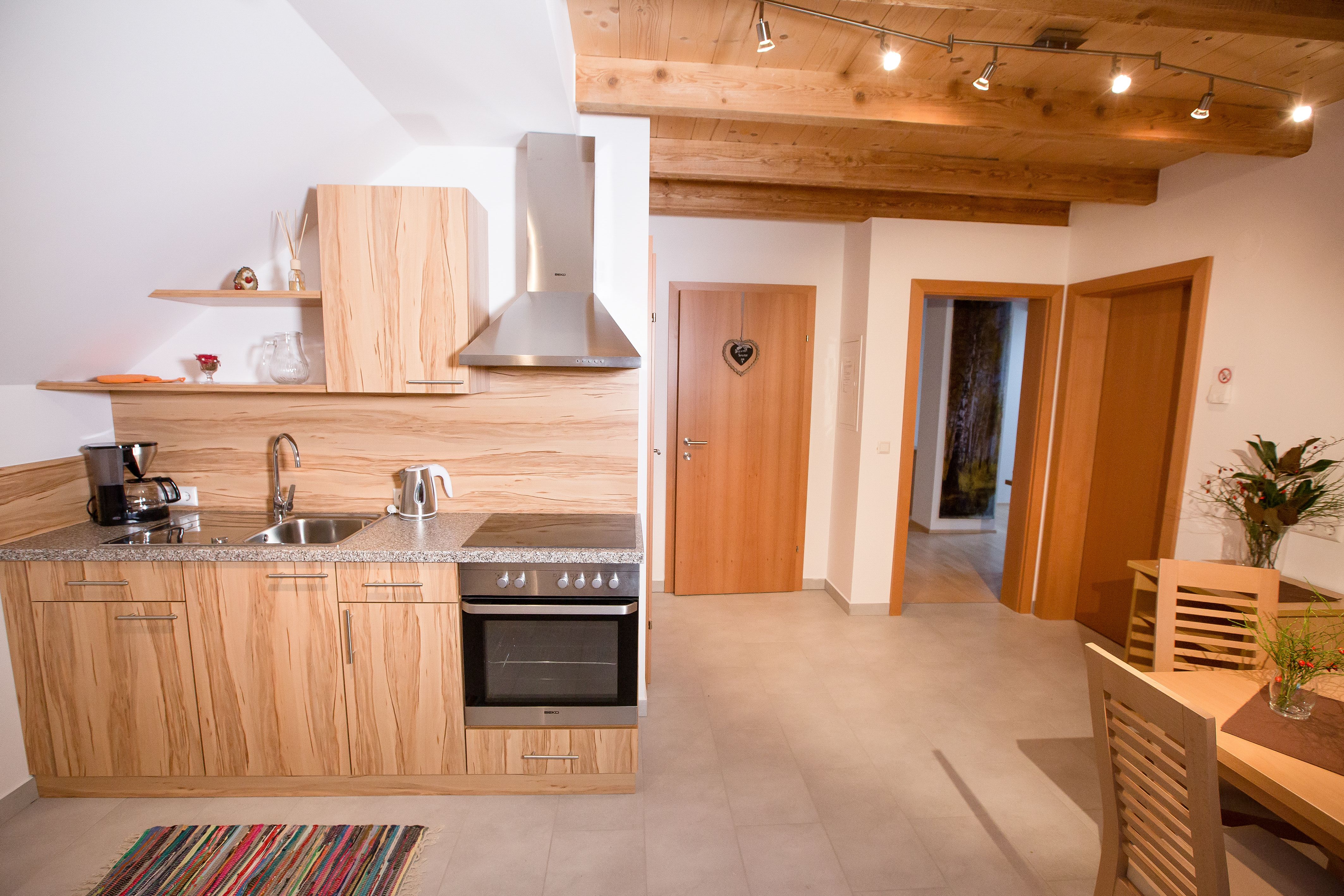 Moderne Küche mit Holzdekor, Esstisch und Blumen.