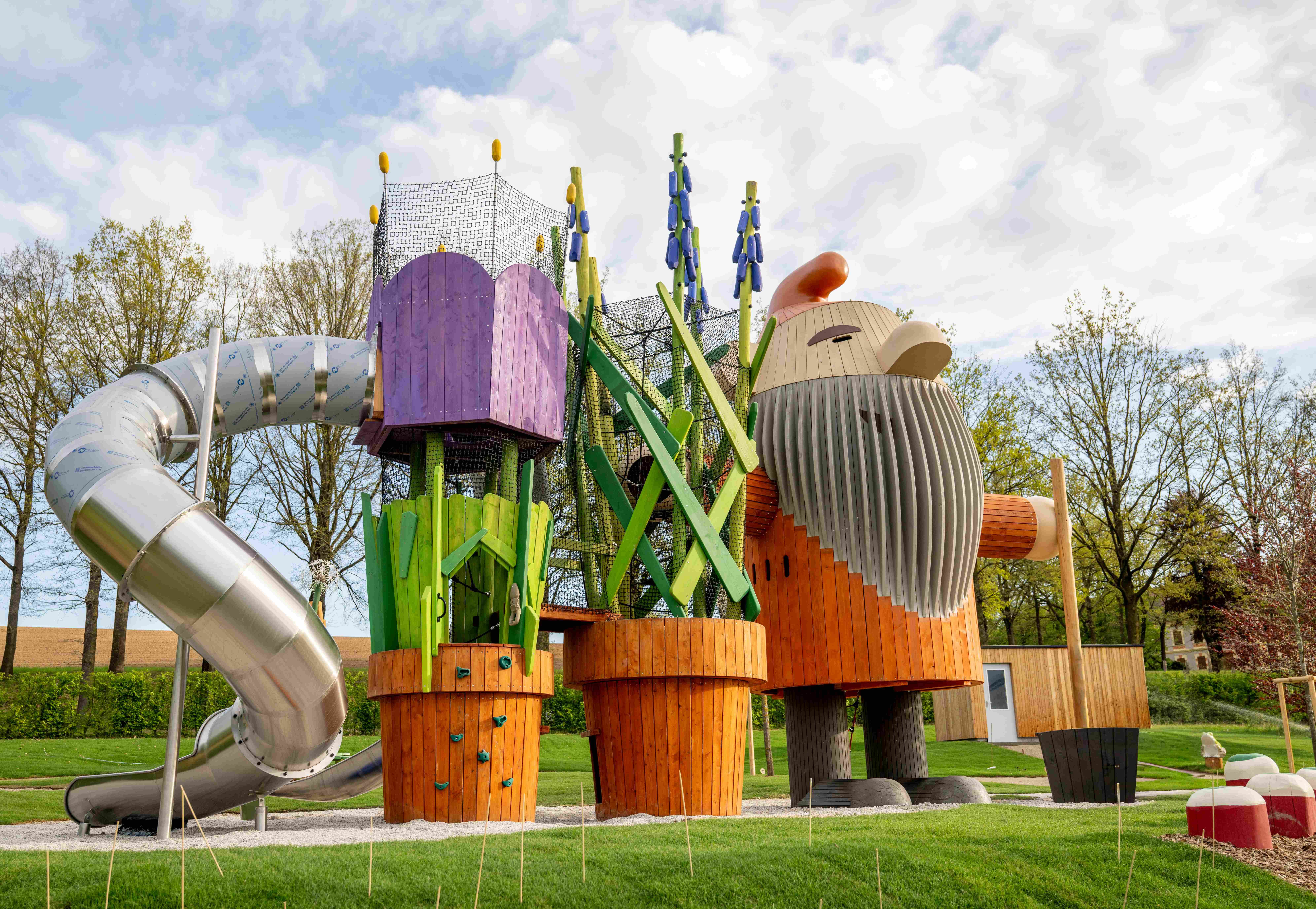 Ein fantasievoller Spielplatz mit einen großen Holzfiguren und einer Rutsche.