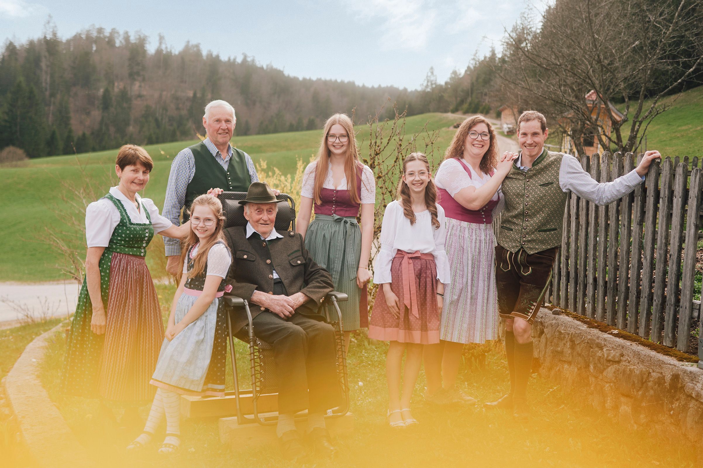 Eine Familie in traditioneller Tracht posiert im Freien vor einer ländlichen Kulisse.