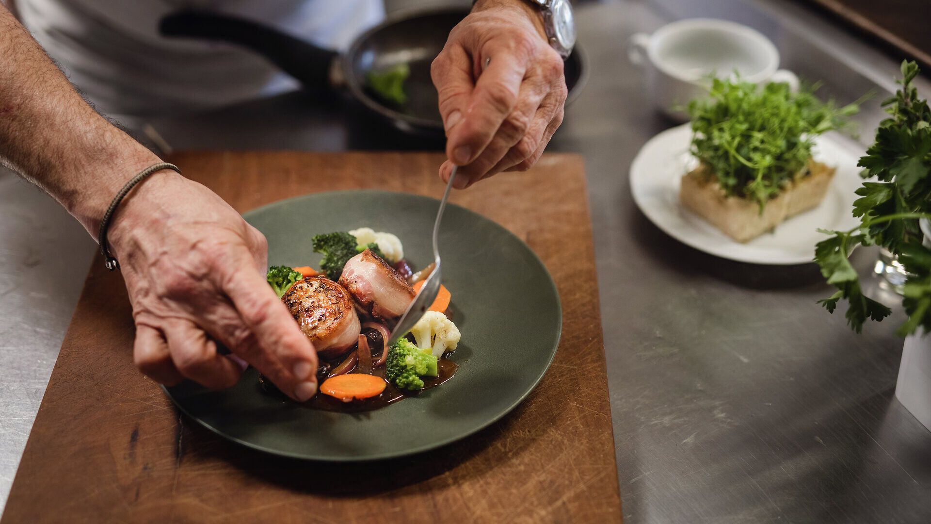 Genießen Sie die exquisite Kombination aus zarten Schweinsmedaillons, umhüllt von knusprigem Speck, serviert auf einer aromatischen Zwiebel-Most-Sauce. Die lila Erdäpfel und Dörrpflaumen verleihen diesem Gericht eine besondere Note, die die Sinne verführt und den Gaumen erfreut.