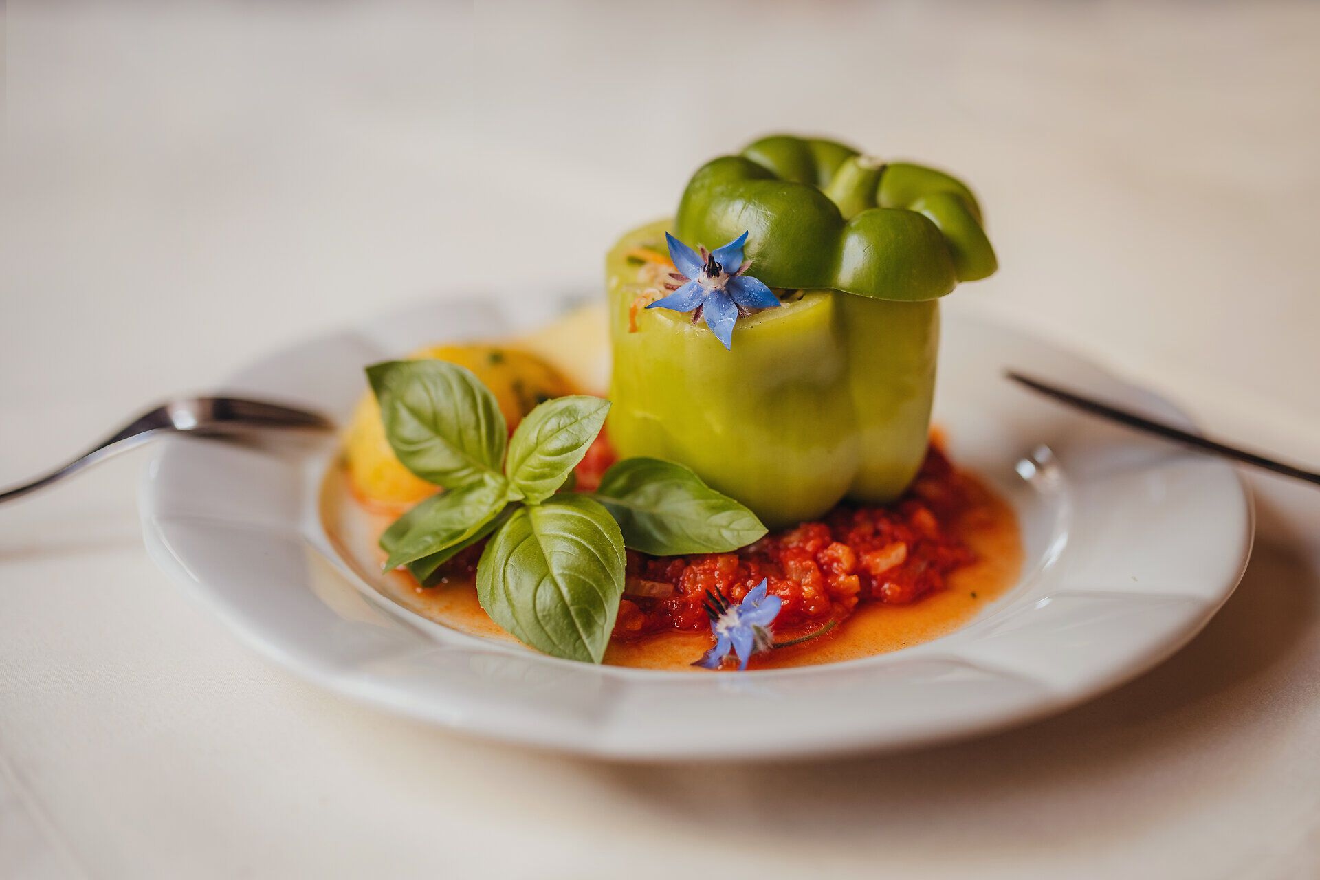 Ein kunstvoll angerichteter vegetarischer gefüllter Paprika, umgeben von einer köstlichen Naturparadeissoße und zarten Petersilerdäpfeln, lädt zum Genießen ein. Die frischen Zutaten und die liebevolle Zubereitung spiegeln die Wirtshauskultur Niederösterreich wider und versprechen ein unvergessliches Geschmackserlebnis.