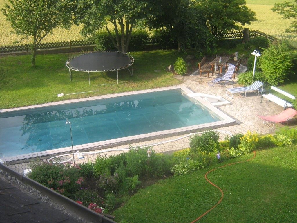 Garten mit Pool, Trampolin und Liegestühlen.