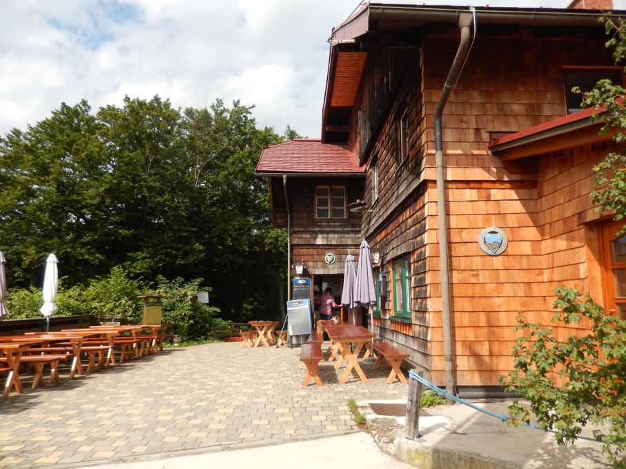 Holzhütte mit Terrasse und Sitzbänken im Freien.