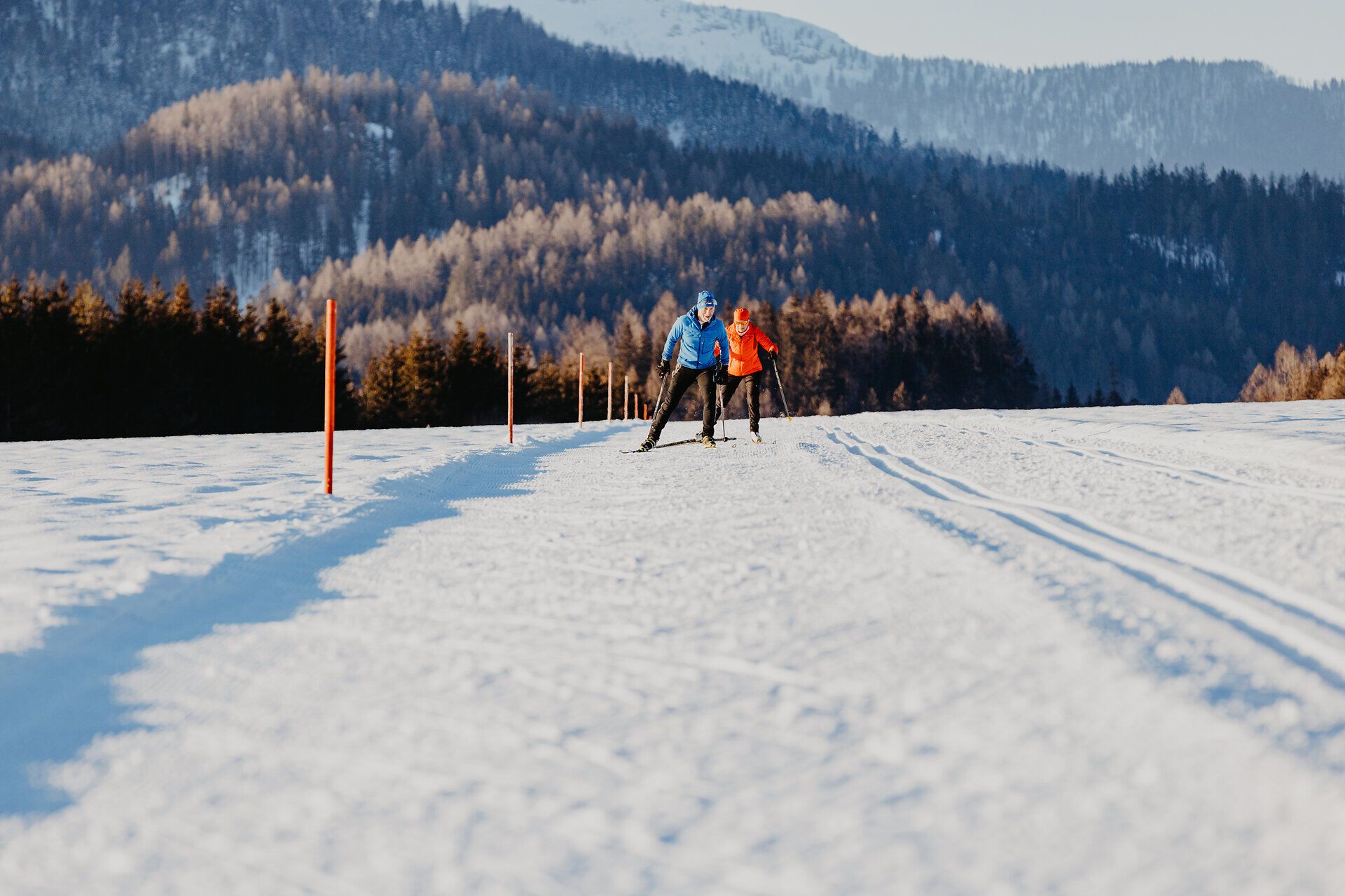 Die glitzernde Schneedecke erstreckt sich über die sanften Hügel, während zwei Skilangläufer in harmonischem Rhythmus die winterliche Landschaft durchqueren. Die klare, kalte Luft ist erfüllt von der Stille der Natur, die nur durch das Geräusch der Skier unterbrochen wird. Ein unvergessliches Erlebnis für alle Wintersportbegeisterten, die die Schönheit der verschneiten Berge genießen möchten.