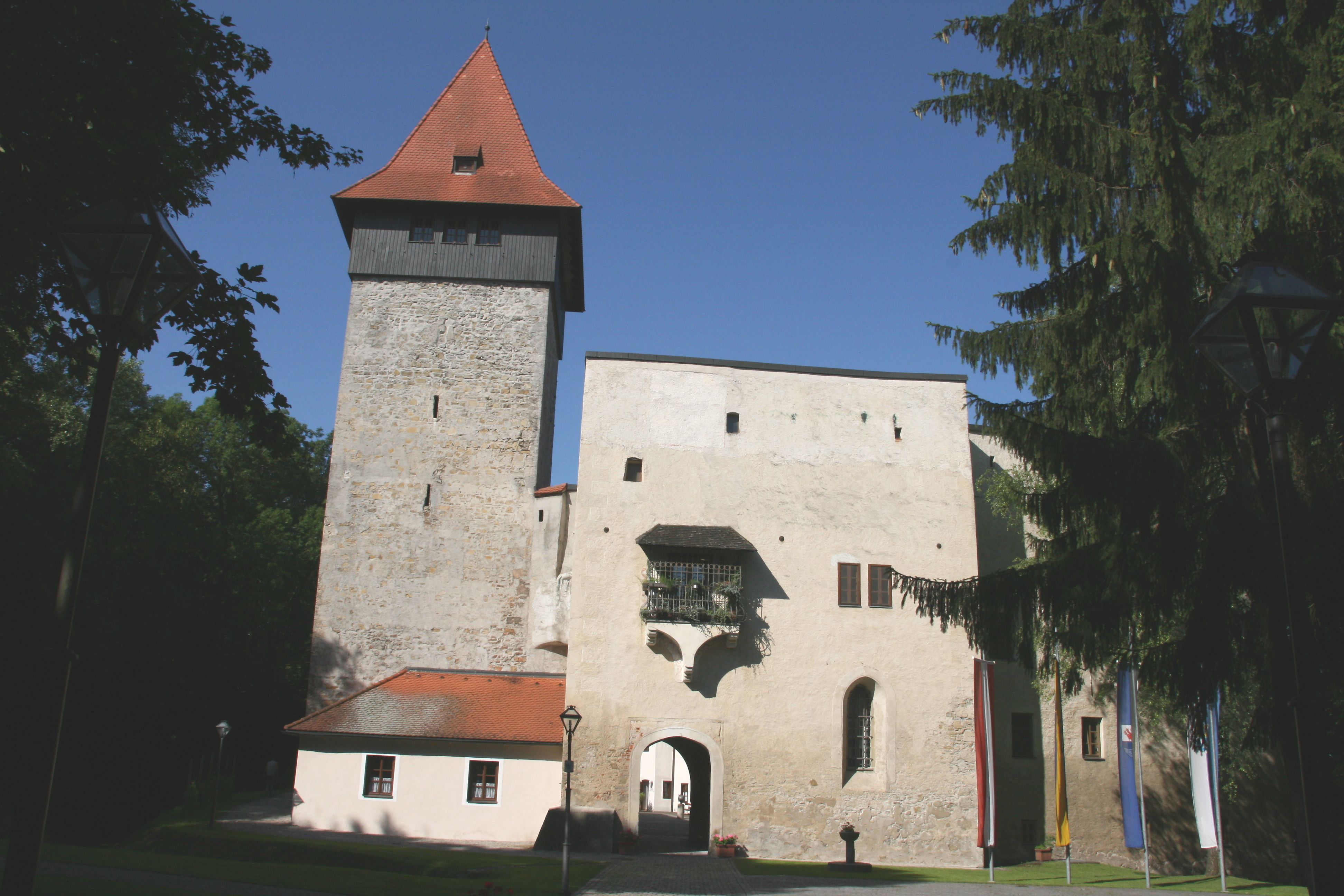 Schloss Ulmerfeld mit Turm und Eingangstor, umgeben von Bäumen.