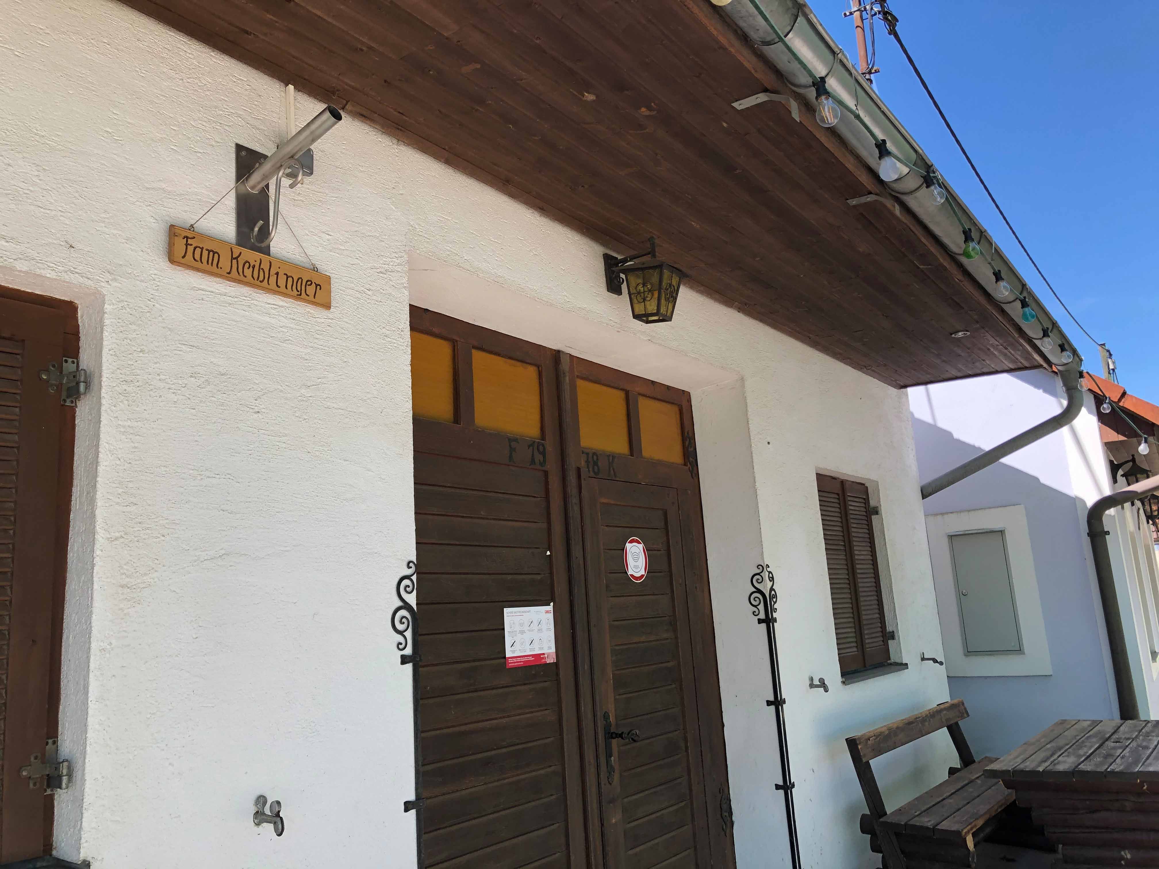 Eingang eines Heurigenlokals mit Holzschild 'Fam. Keiblinger'.